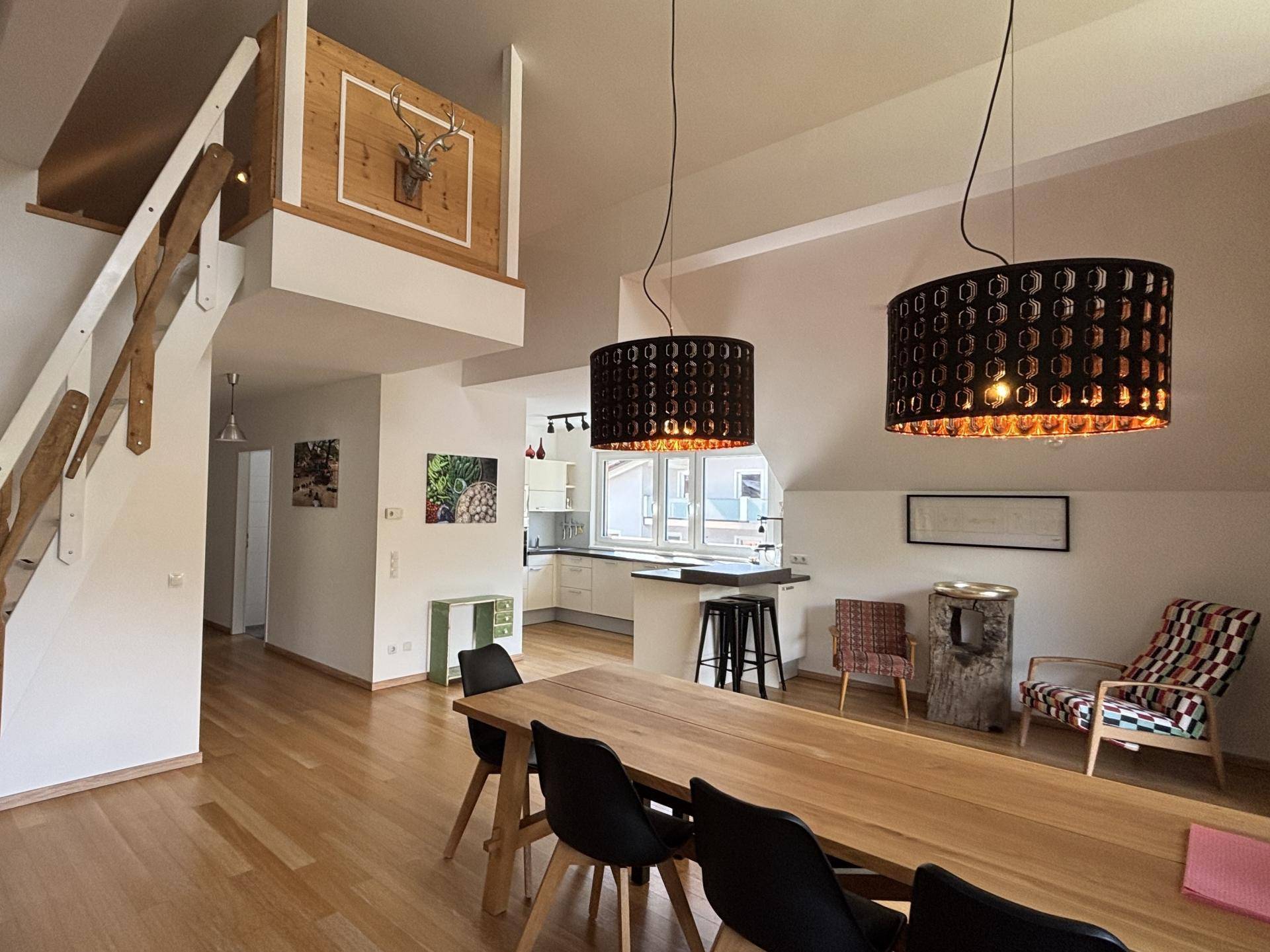 Geräumiger Wohn-Essbereich mit Holzboden, offener Küche und Treppe zum oberen Bereich.