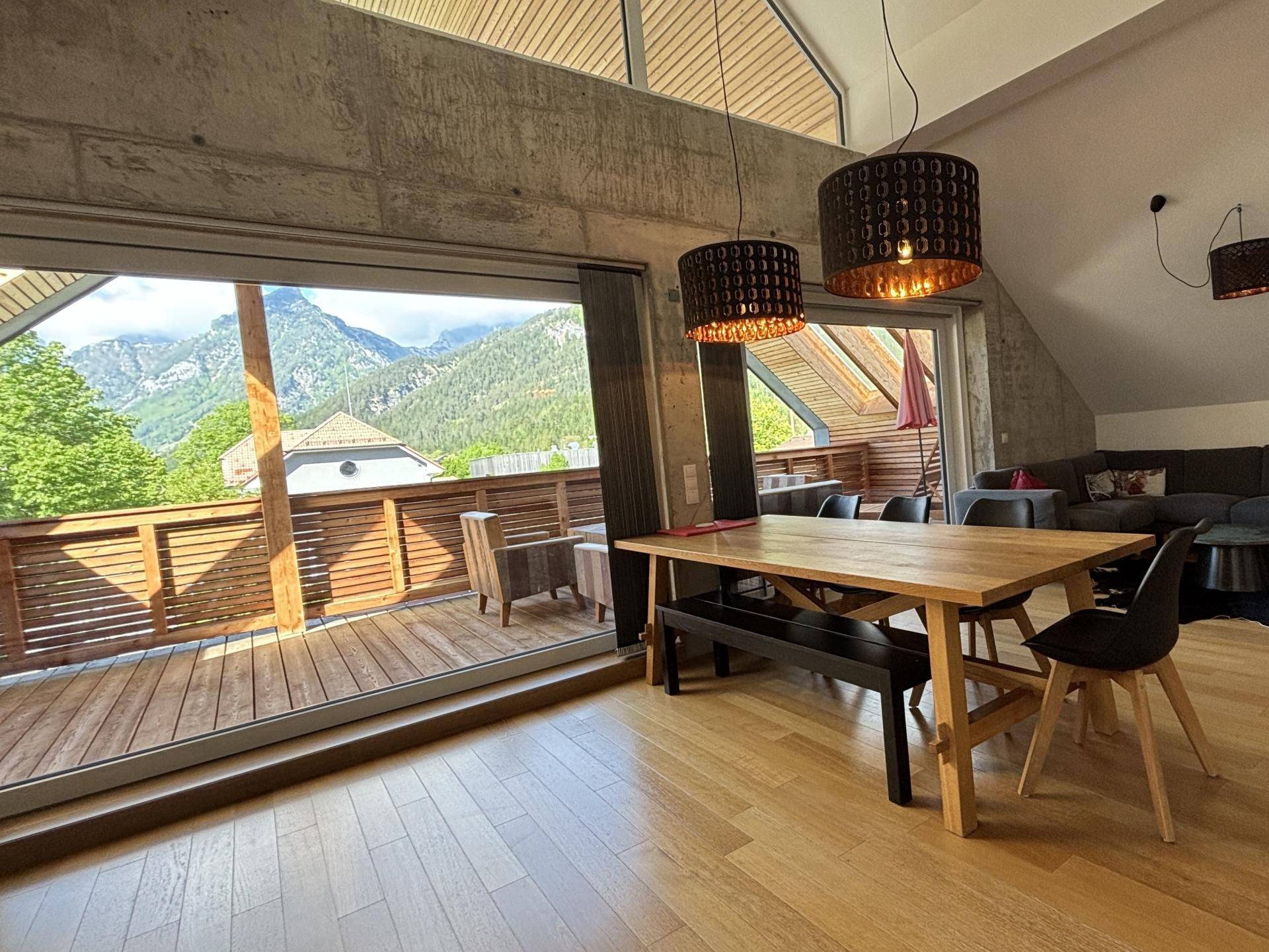 Heller Essbereich mit Holztisch und Panoramablick auf die Berge von der Terrasse.