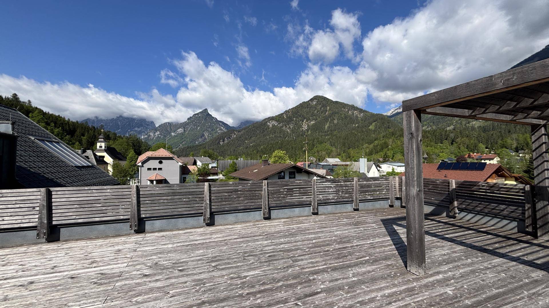 Große Holzterrasse mit Pergola und weitem Blick auf die umliegende Berglandschaft.