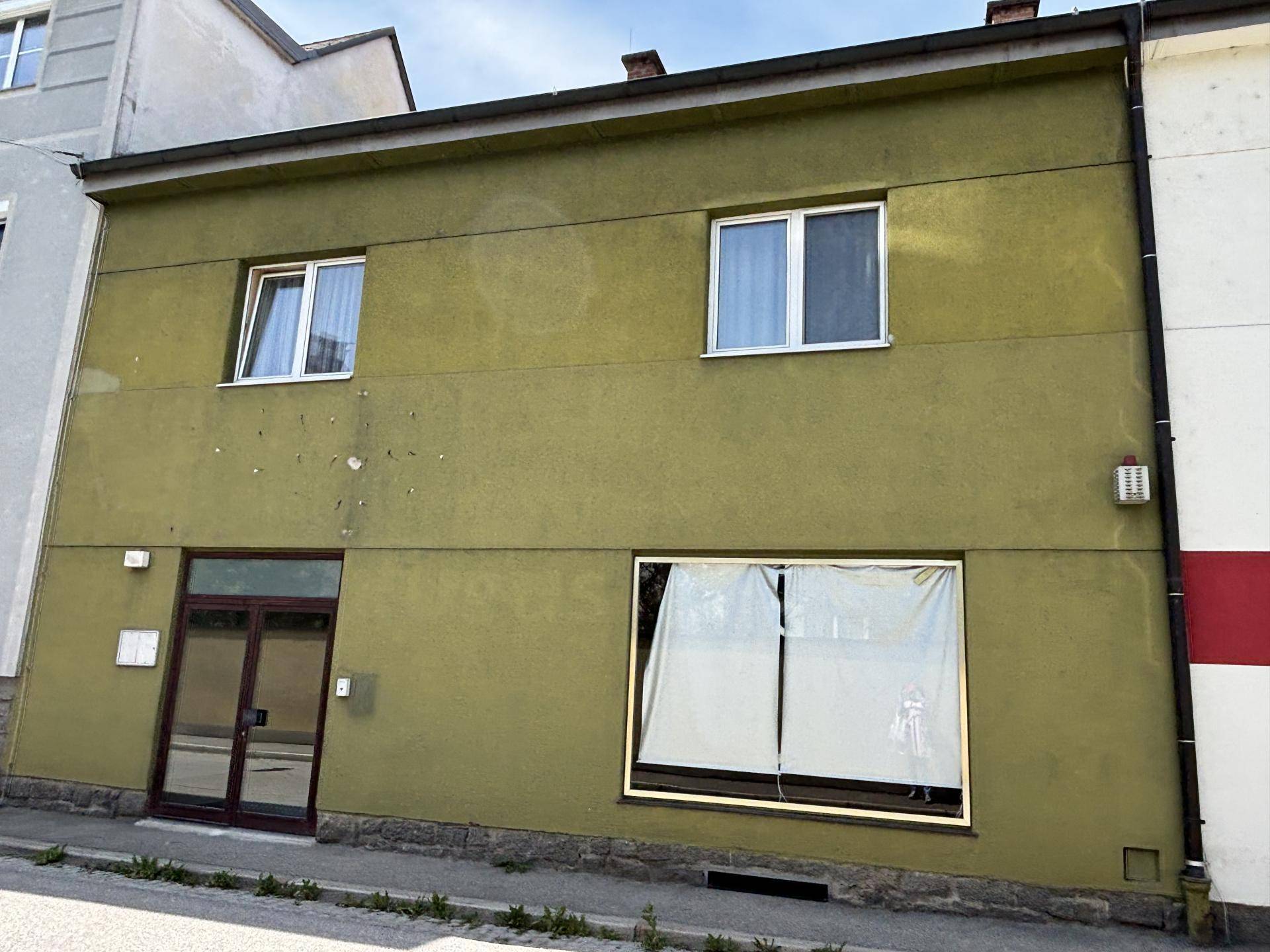 Fassade eines Gebäudes mit olivgrünem Putz, großen Fenstern und klaren Linien.