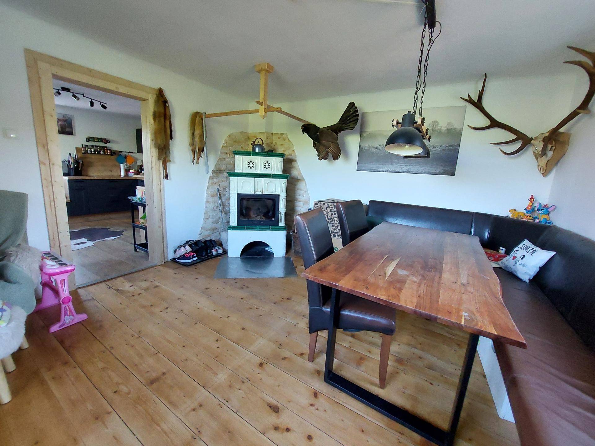 Gemütlicher Essbereich mit Holztisch, Eckbank und traditionellem Kachelofen sowie Jagdtrophäen.