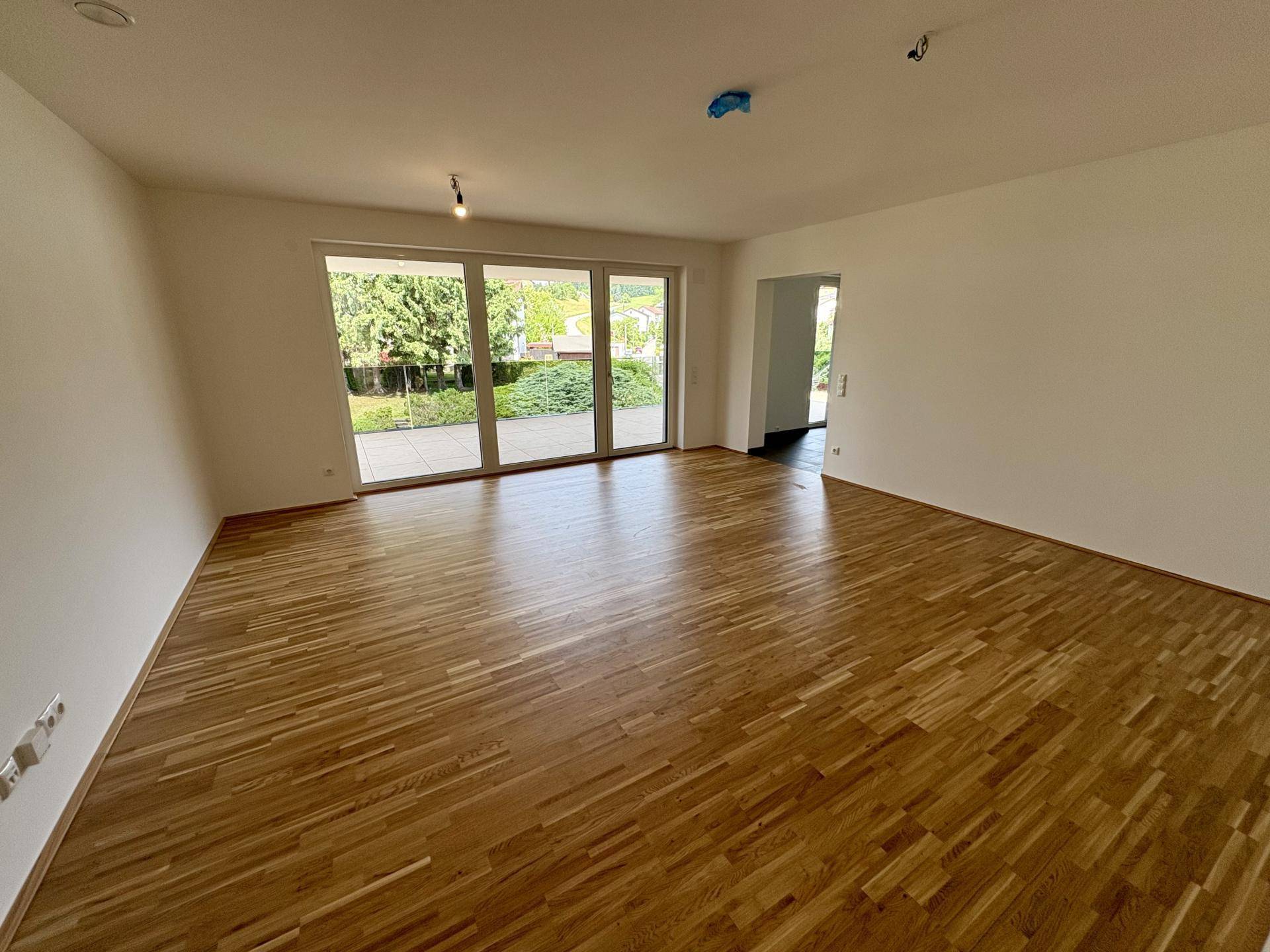 Heller Wohnraum mit Eichenparkettboden und großen Schiebetüren zur Terrasse.