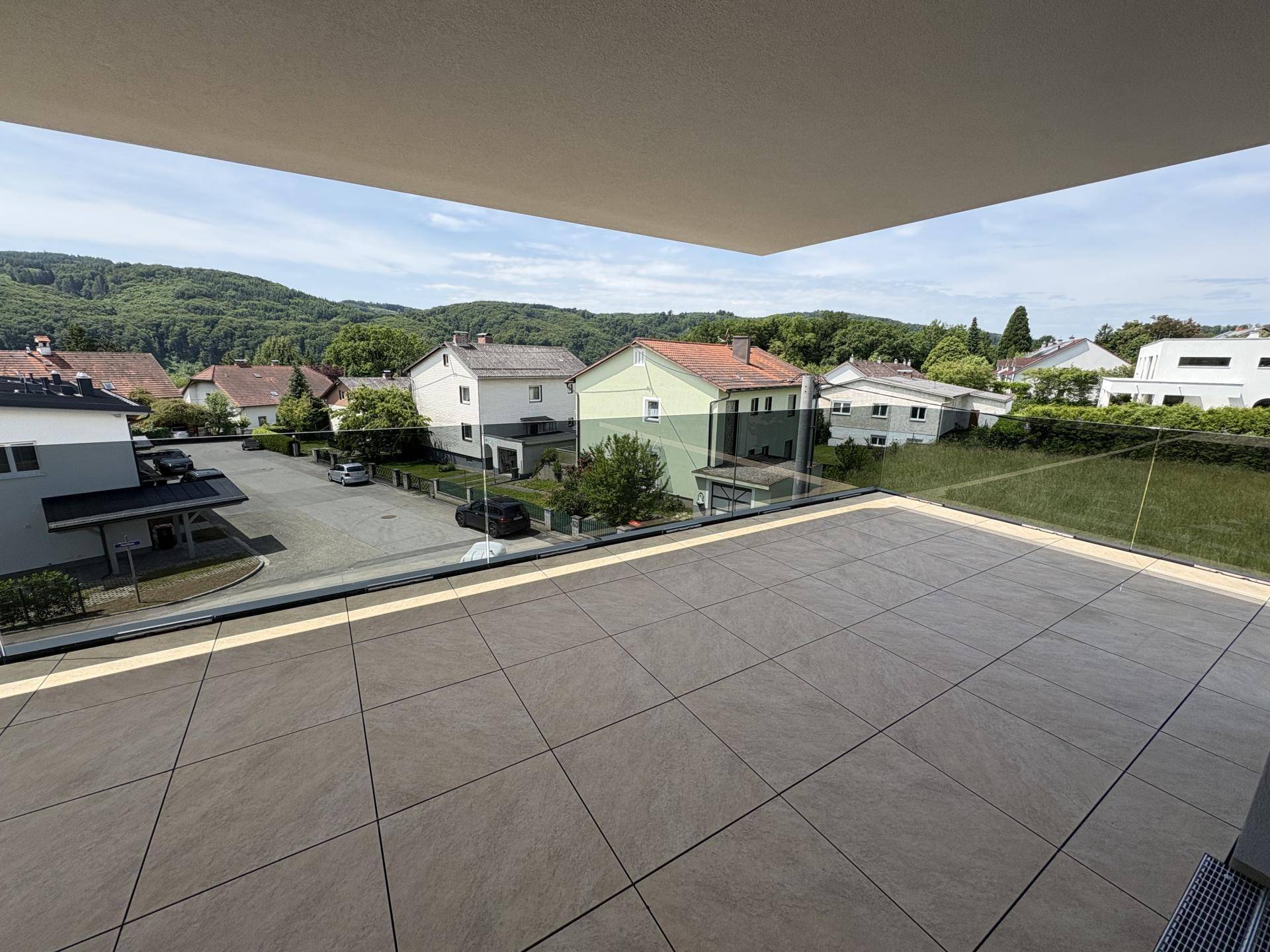 Geräumige Terrasse mit moderner Fliesenoptik und weitem Blick über die grüne Umgebung.