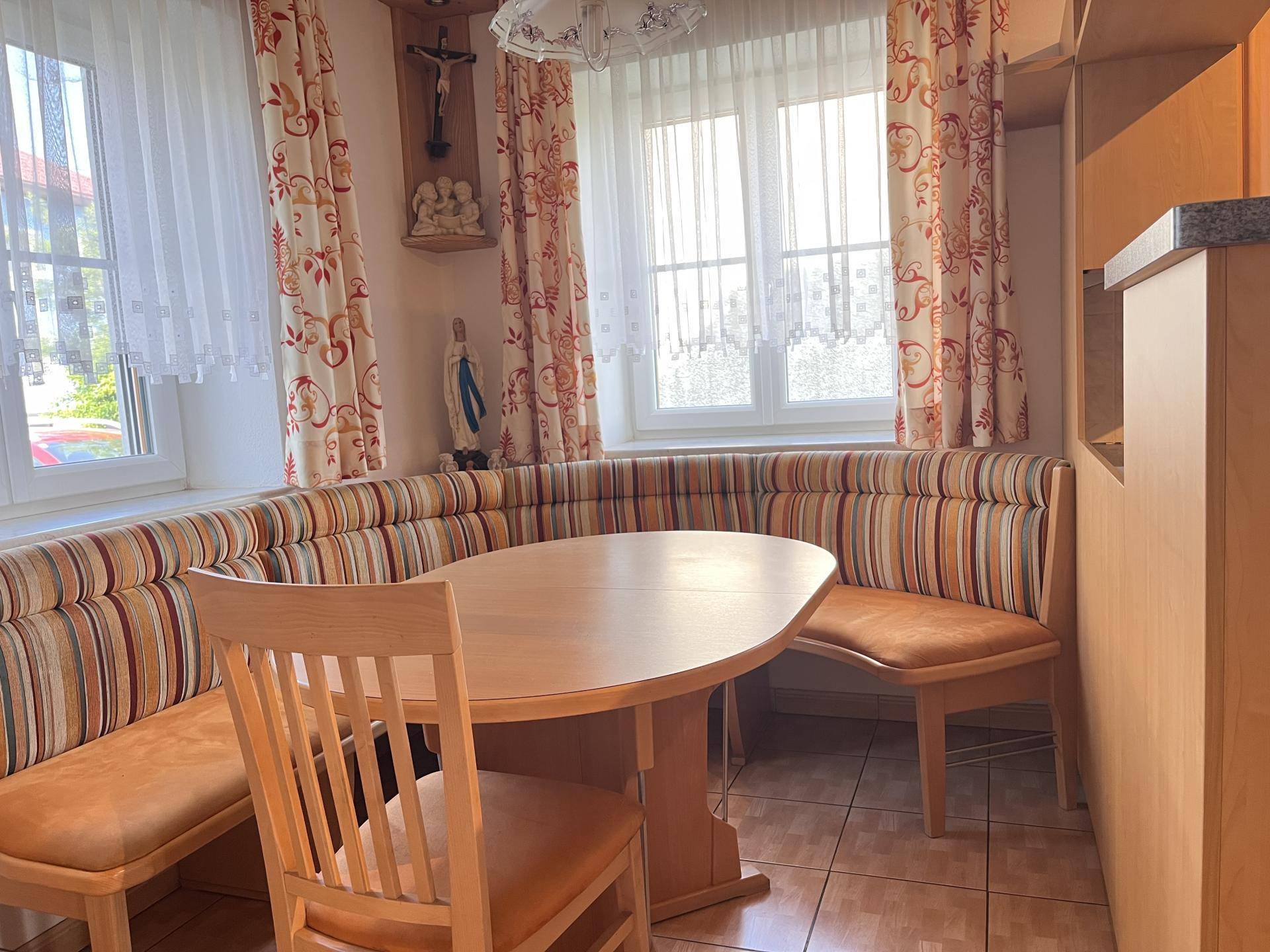Traditionelle Essecke mit Eckbank, Holztisch und Fenstern mit Vorhängen.