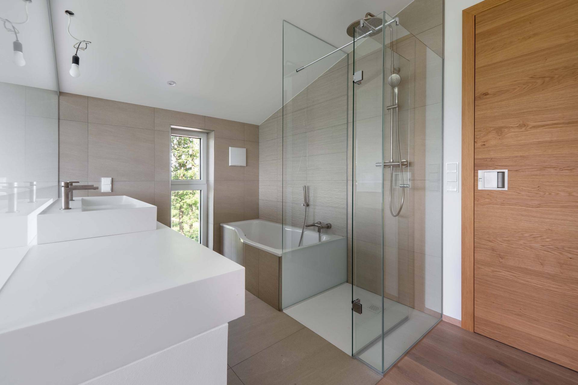 Modernes Badezimmer mit Doppelwaschbecken, Badewanne und großer begehbarer Dusche sowie Fenster.