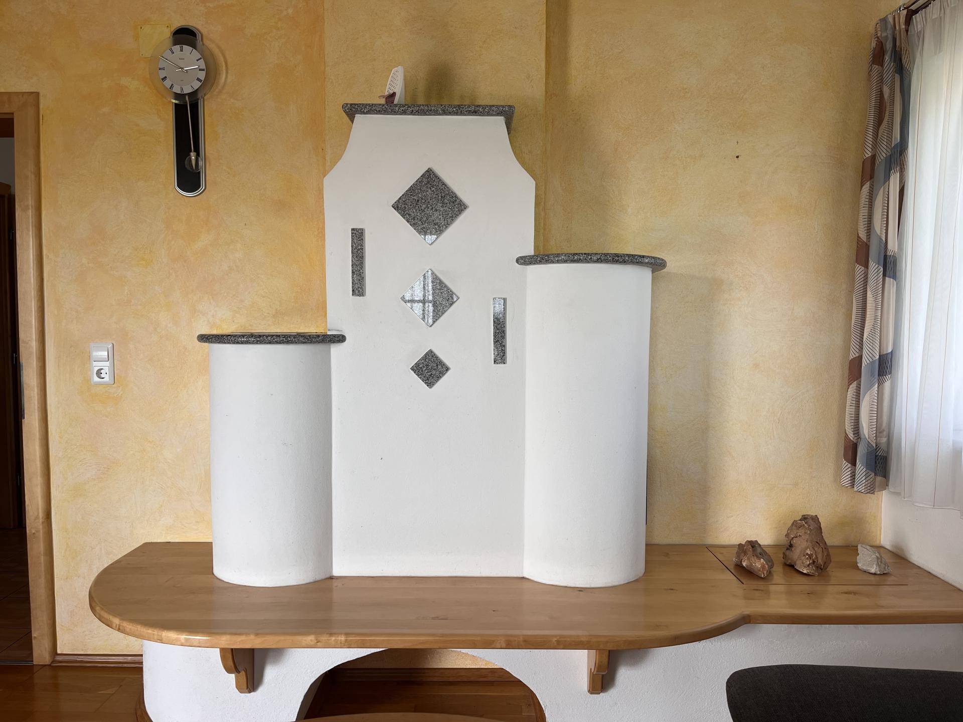 Detailansicht eines traditionellen Kachelofens mit Sitzbank im Wohnzimmer.