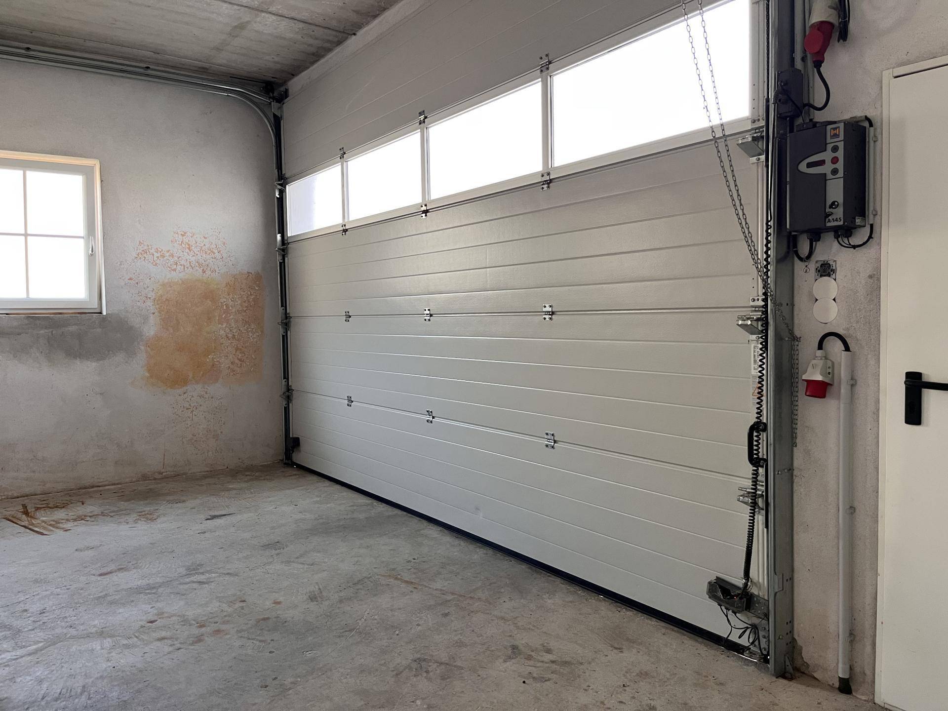 Geräumige Garage mit Sektionaltor und Fenster, bietet Platz für Fahrzeuge.