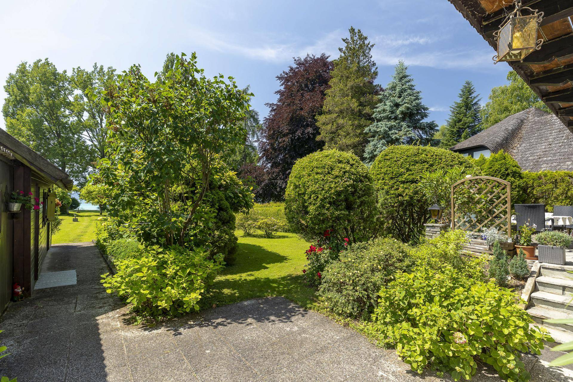 Steinweg führt durch einen üppigen Garten mit verschiedenen Pflanzen und Sträuchern.