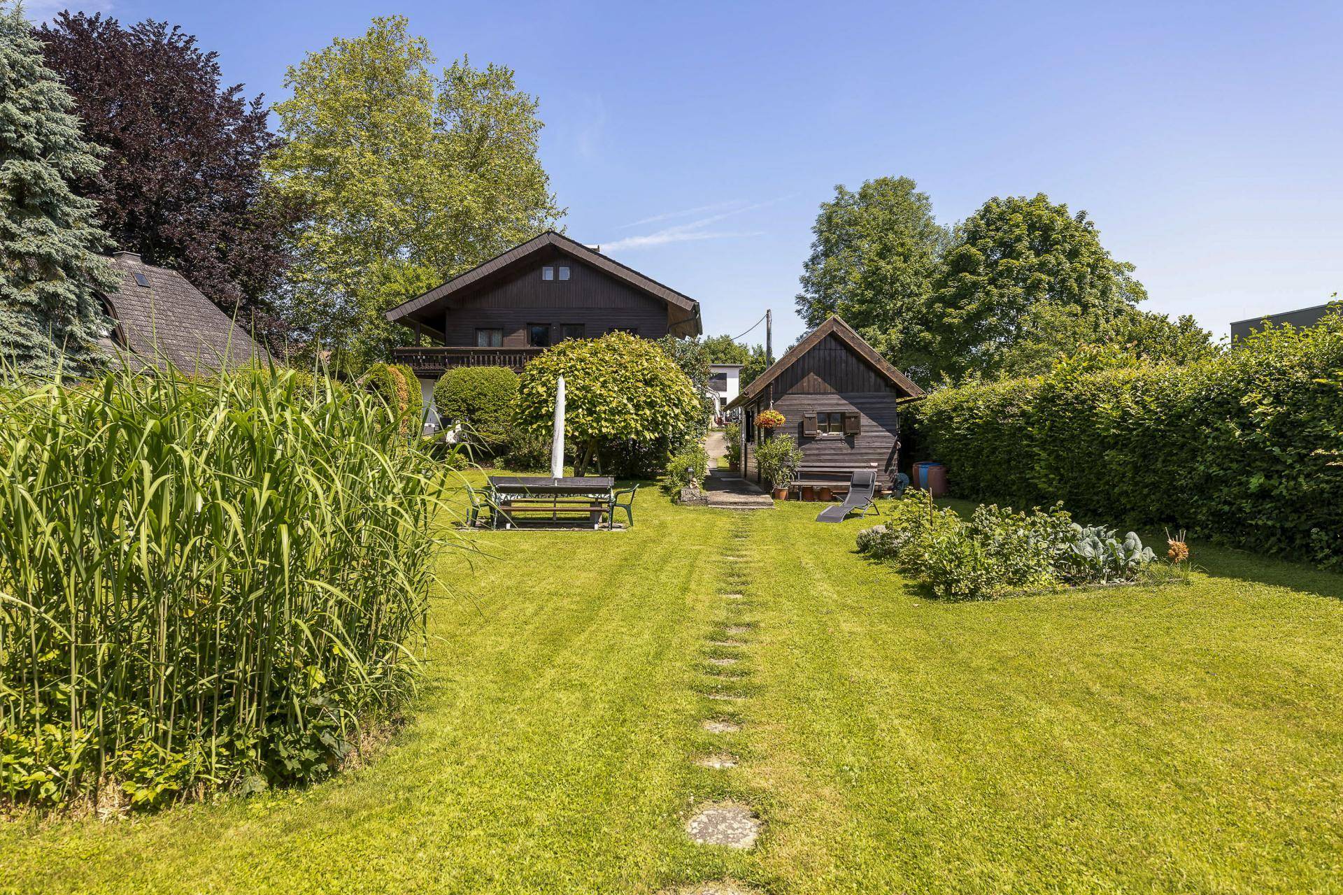 Großer Garten mit Rasenweg, Gartenhaus und Sitzbereich vor dem Haupthaus.