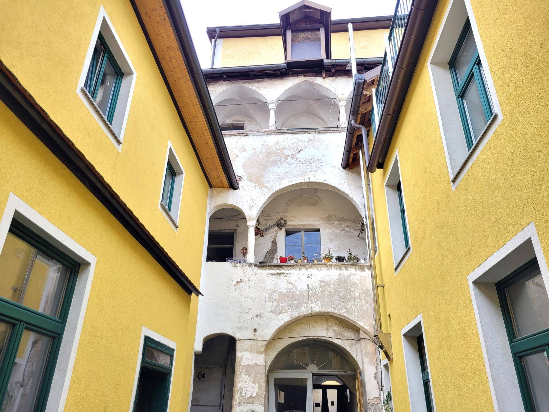 Innenhof mit gelben Fassaden und historischen Arkaden, die eine charmante Atmosphäre schaffen.