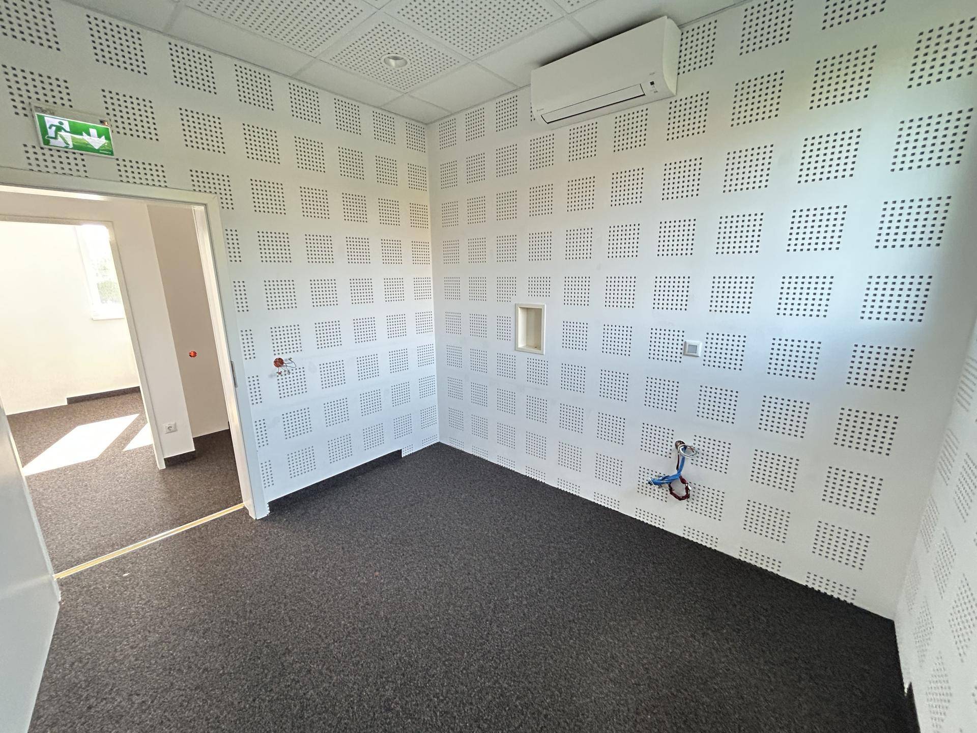 Büro mit Akustikpaneelen, Teppichboden und einer Klimaanlage an der Decke, bereit zur Nutzung.
