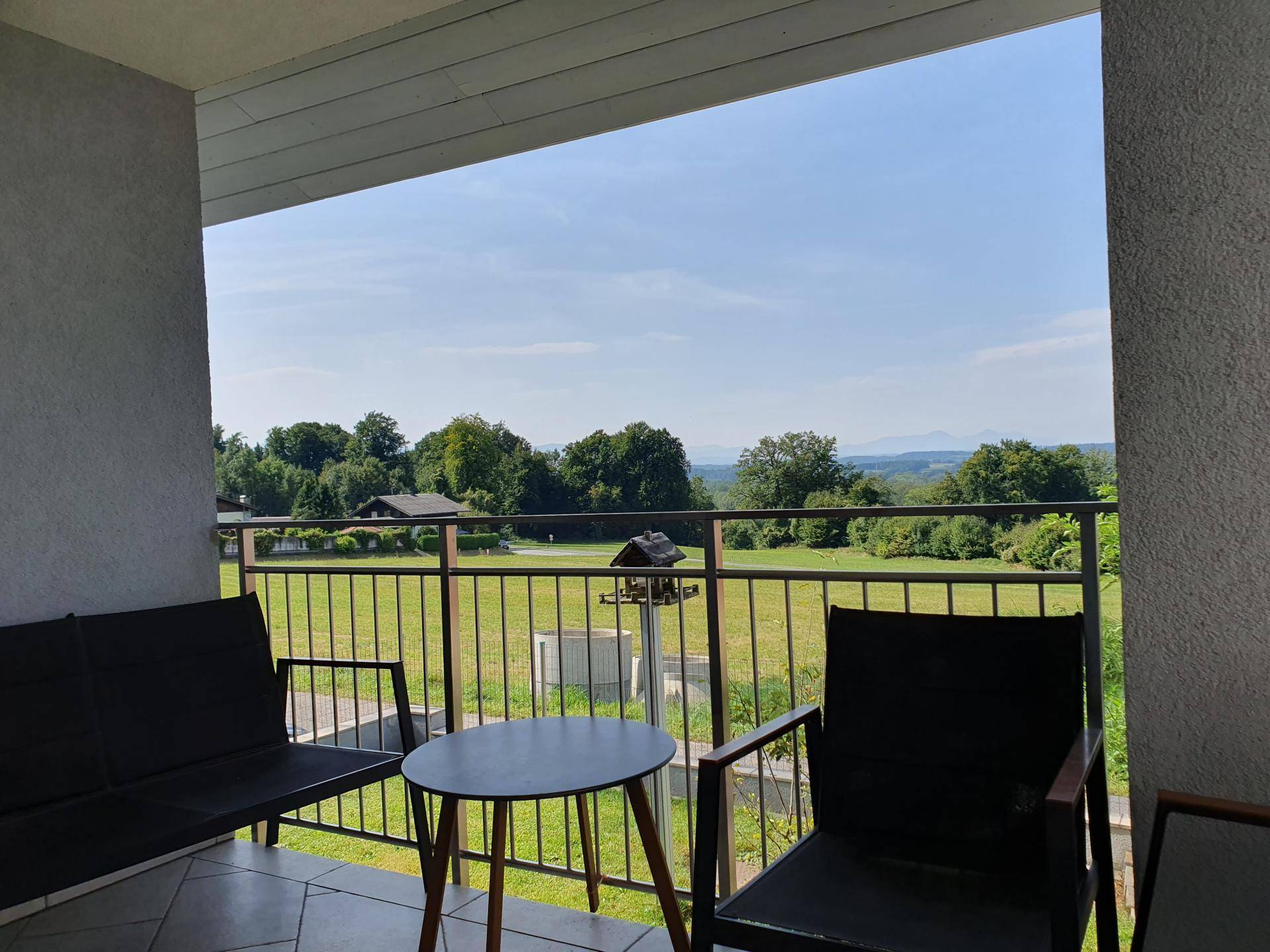 Gemütlicher Balkon mit Sitzgelegenheiten und weitem Blick über grüne Felder und Landschaft.
