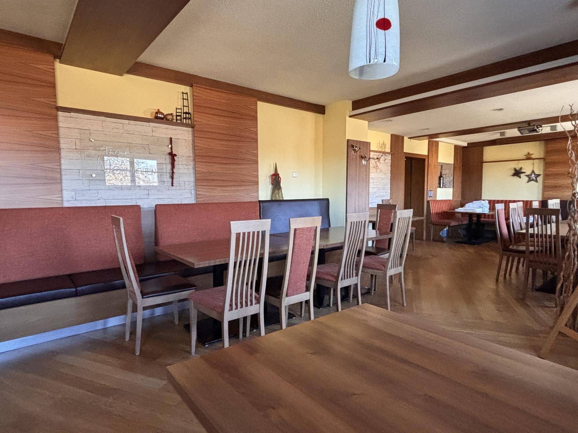 Geräumiger Speisesaal mit Holztischen, Bänken und warmen Holzakzenten an den Wänden.