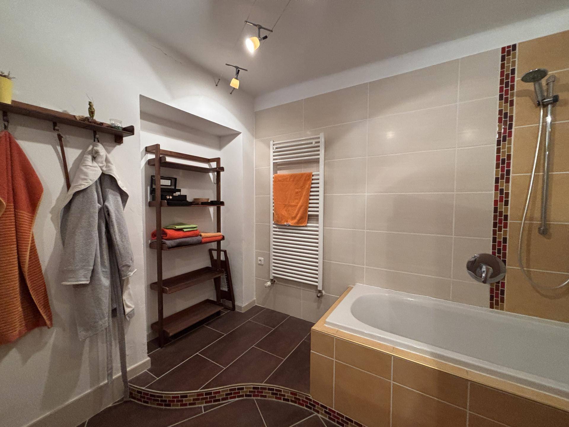 Modernes Badezimmer mit Badewanne, Duschbereich und beigefarbenen Wandfliesen.