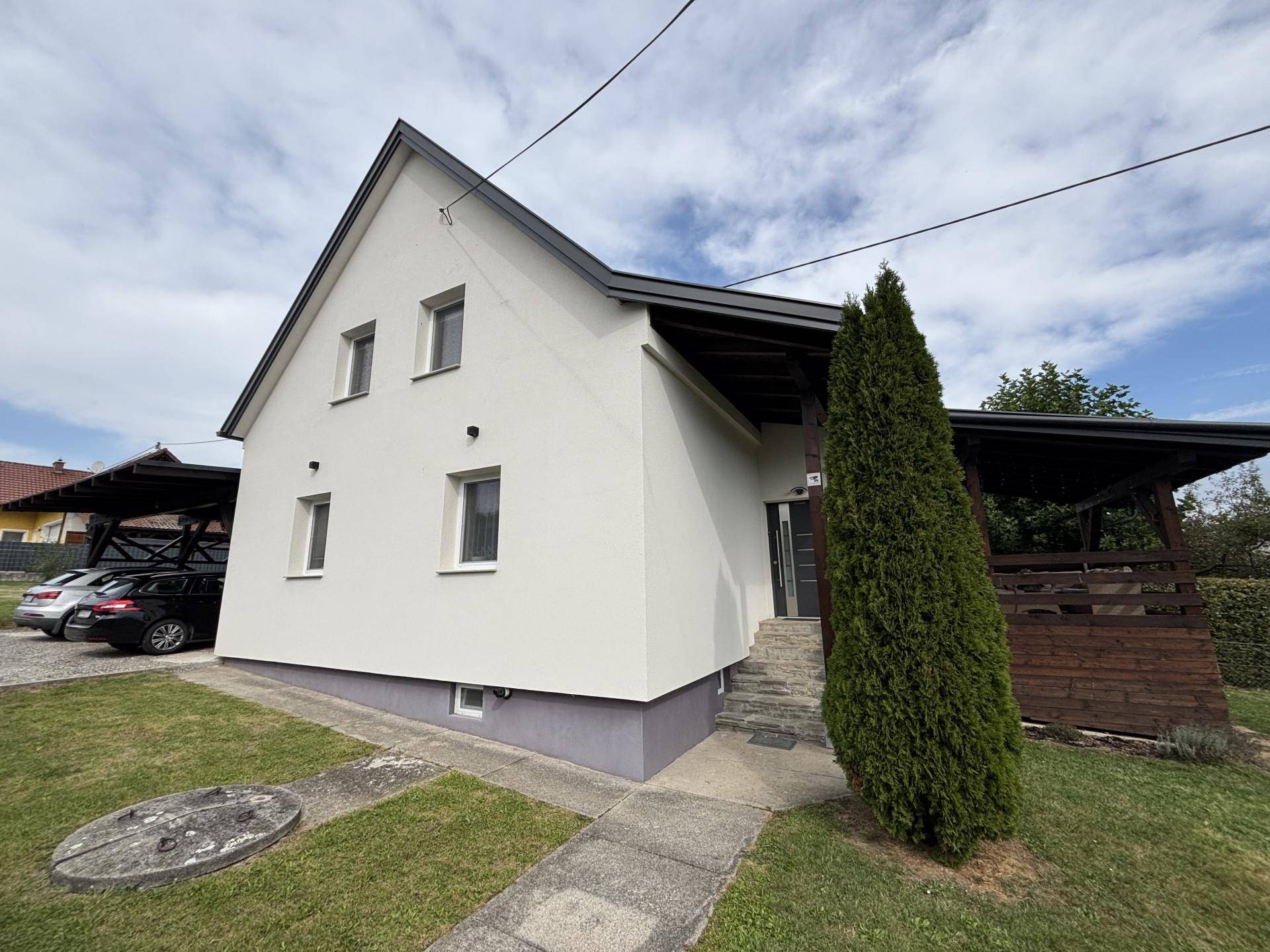 Vorderansicht eines gepflegten Einfamilienhauses mit Vorgarten und überdachtem Carport.