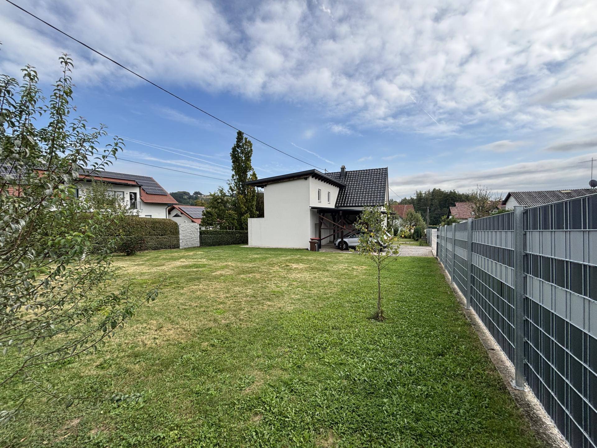 Weitläufiger Gartenbereich mit Rasenfläche und Blick auf das moderne Einfamilienhaus.