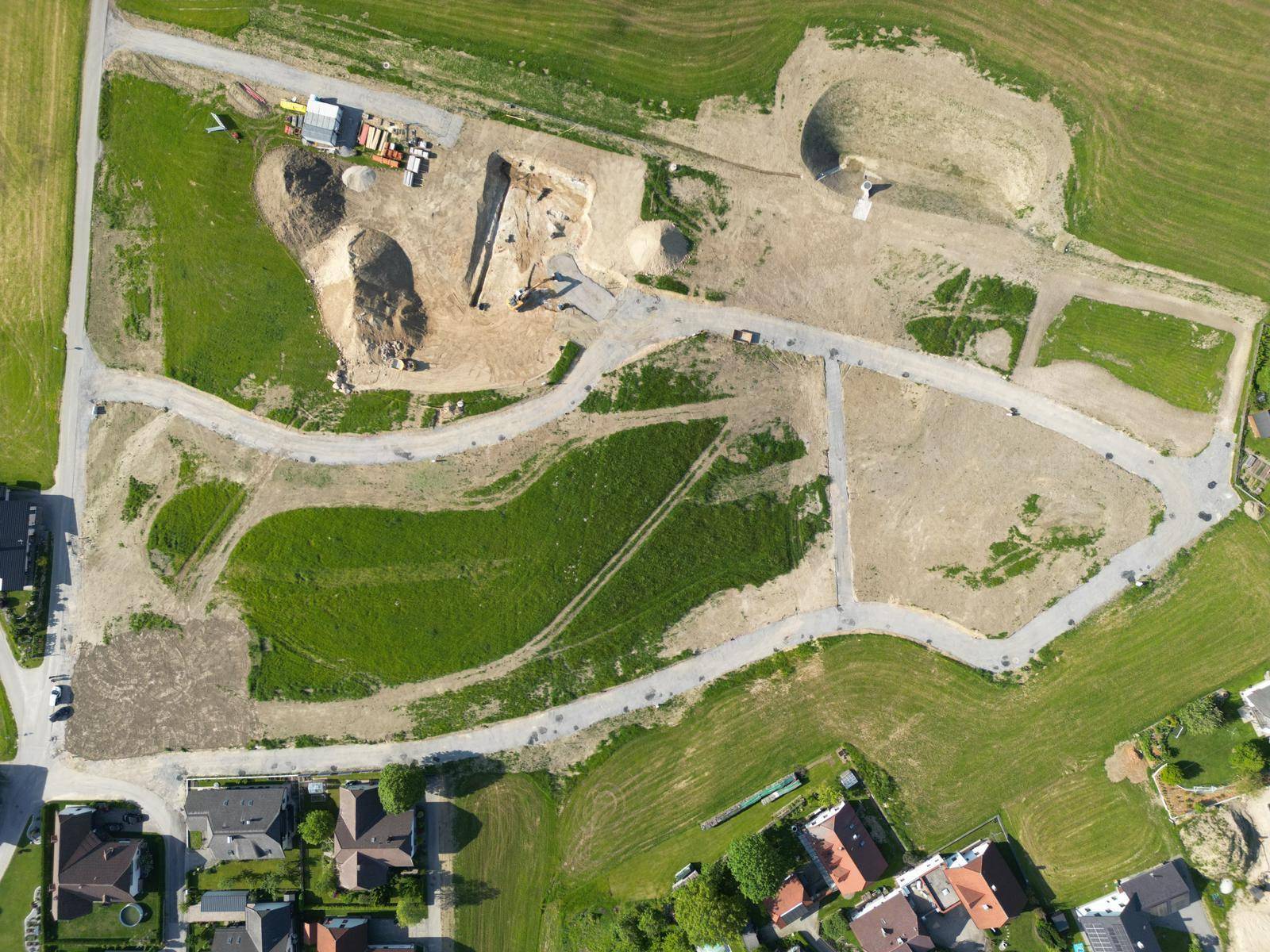 Detaillierte Luftaufnahme eines Baugebiets mit vorbereiteten Parzellen und Erdarbeiten für neue Gebäude.