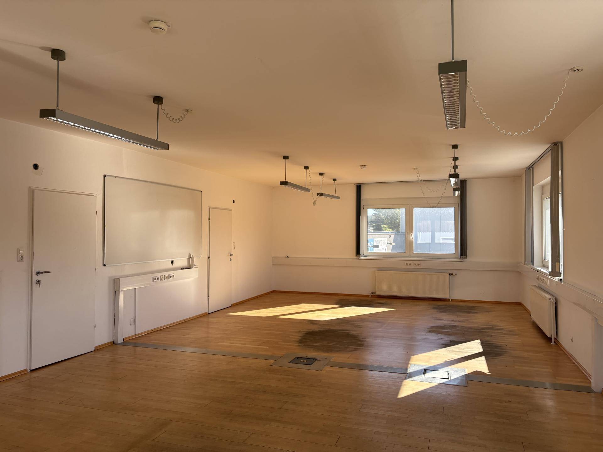 Großer, leerer Büroraum mit Holzboden und mehreren Fenstern, bereit zur individuellen Gestaltung.