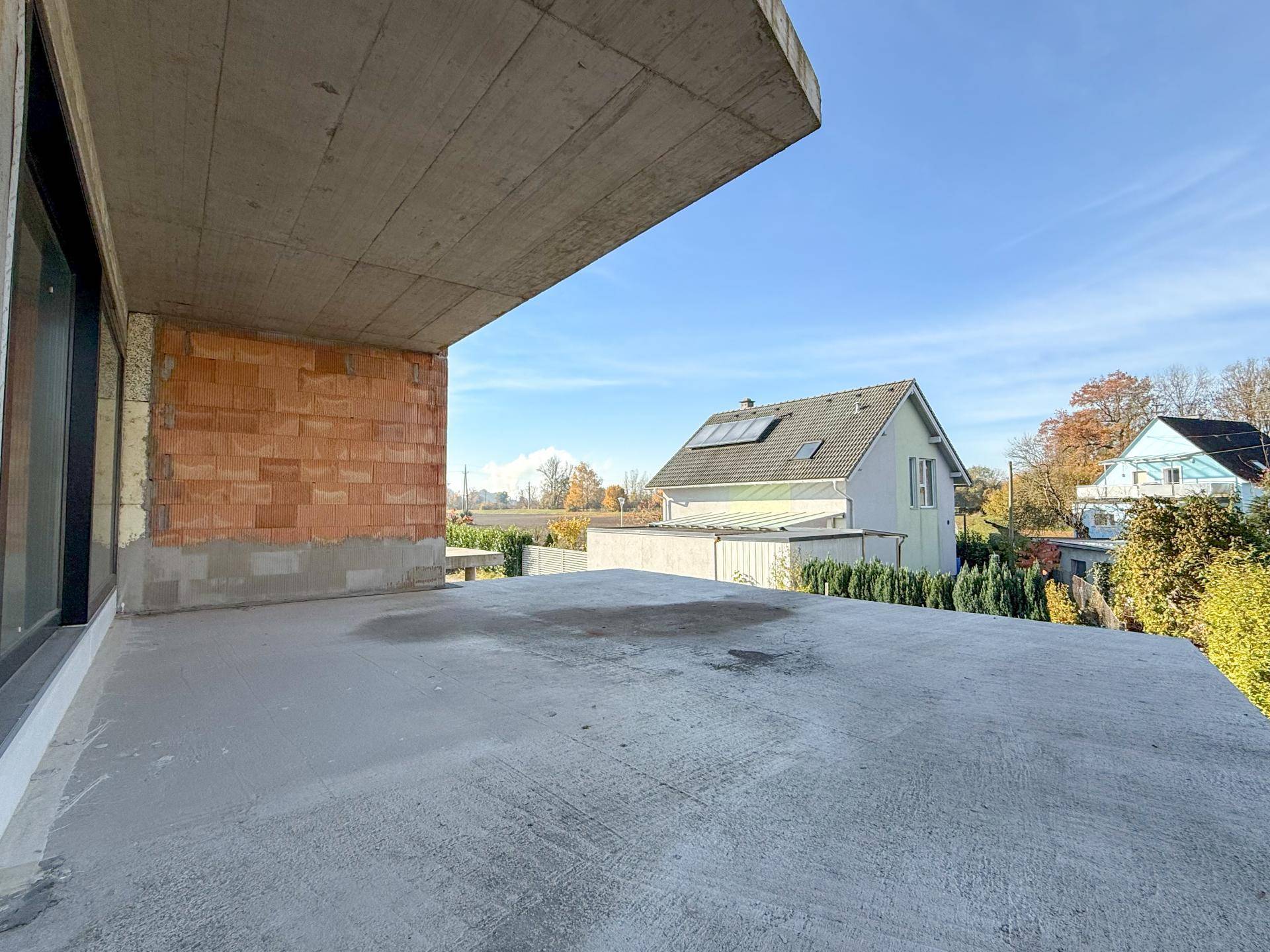 Unfertiger Balkon mit Betonboden und Blick auf die Nachbarschaft, noch im Bau.