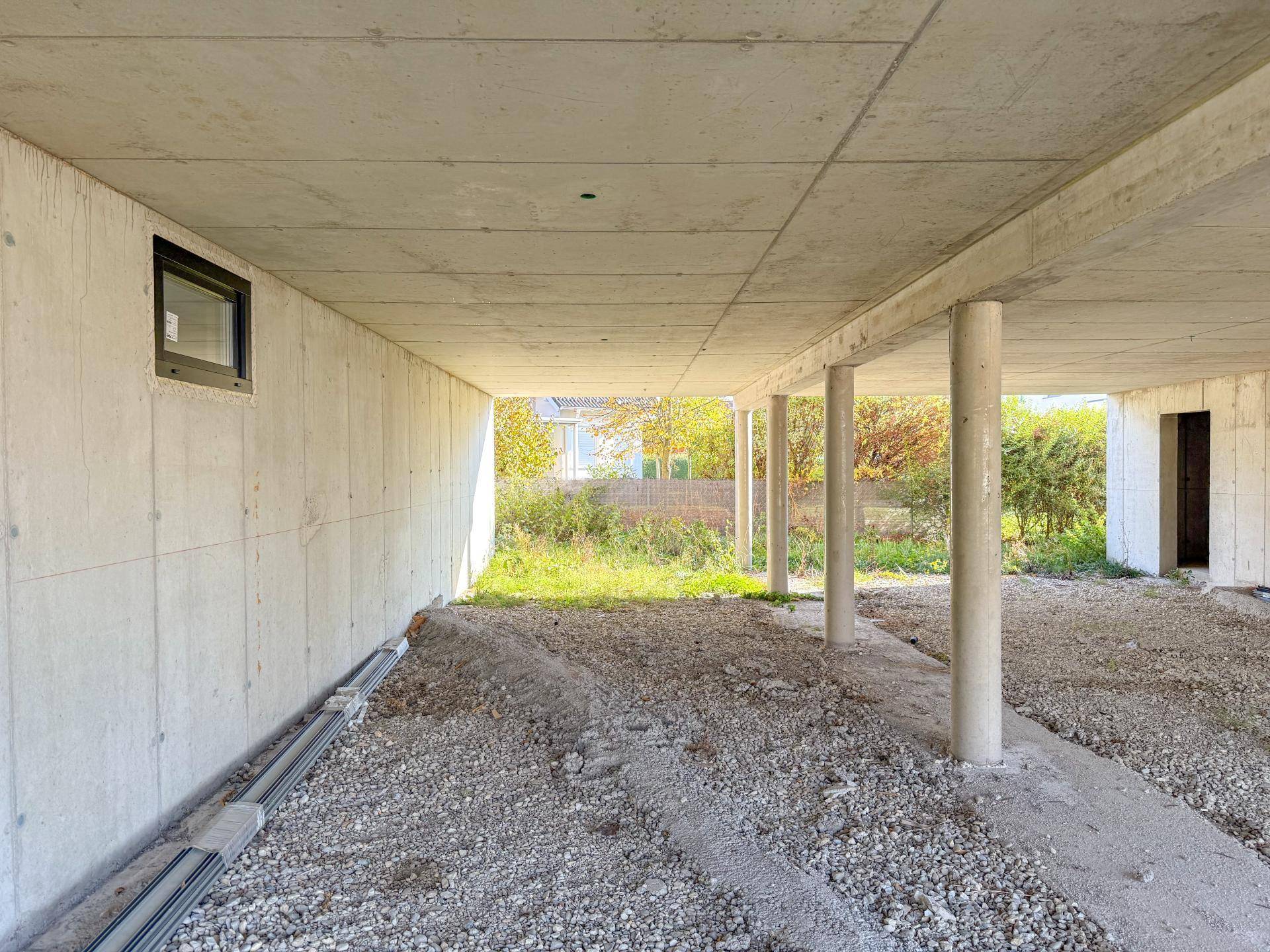 Offener Unterbau des Gebäudes mit Betonpfeilern und natürlichem Lichteinfall.