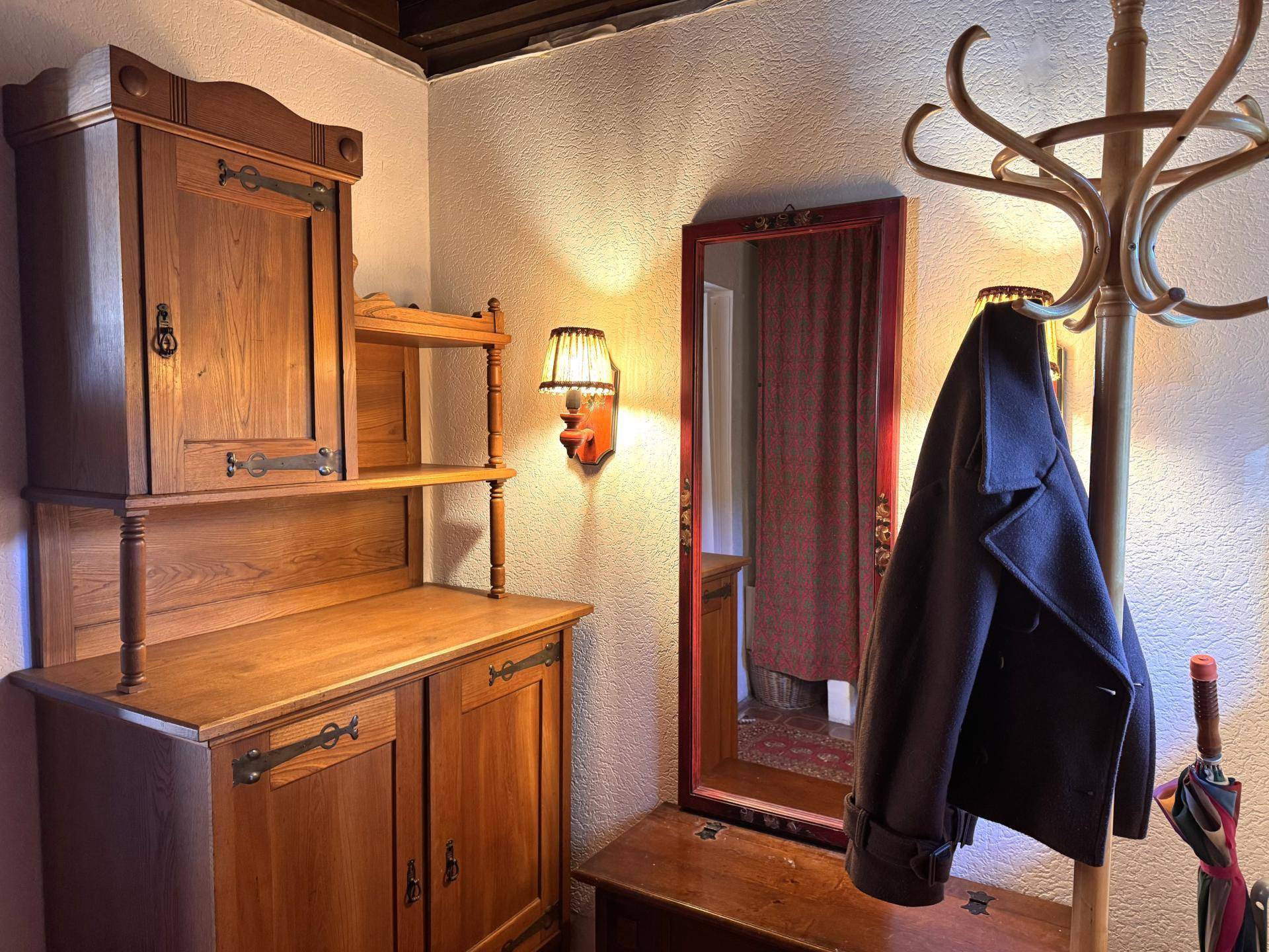 Gemütlicher Flur mit Holzmöbeln, Spiegel und Garderobe, strahlt traditionellen Charme aus.