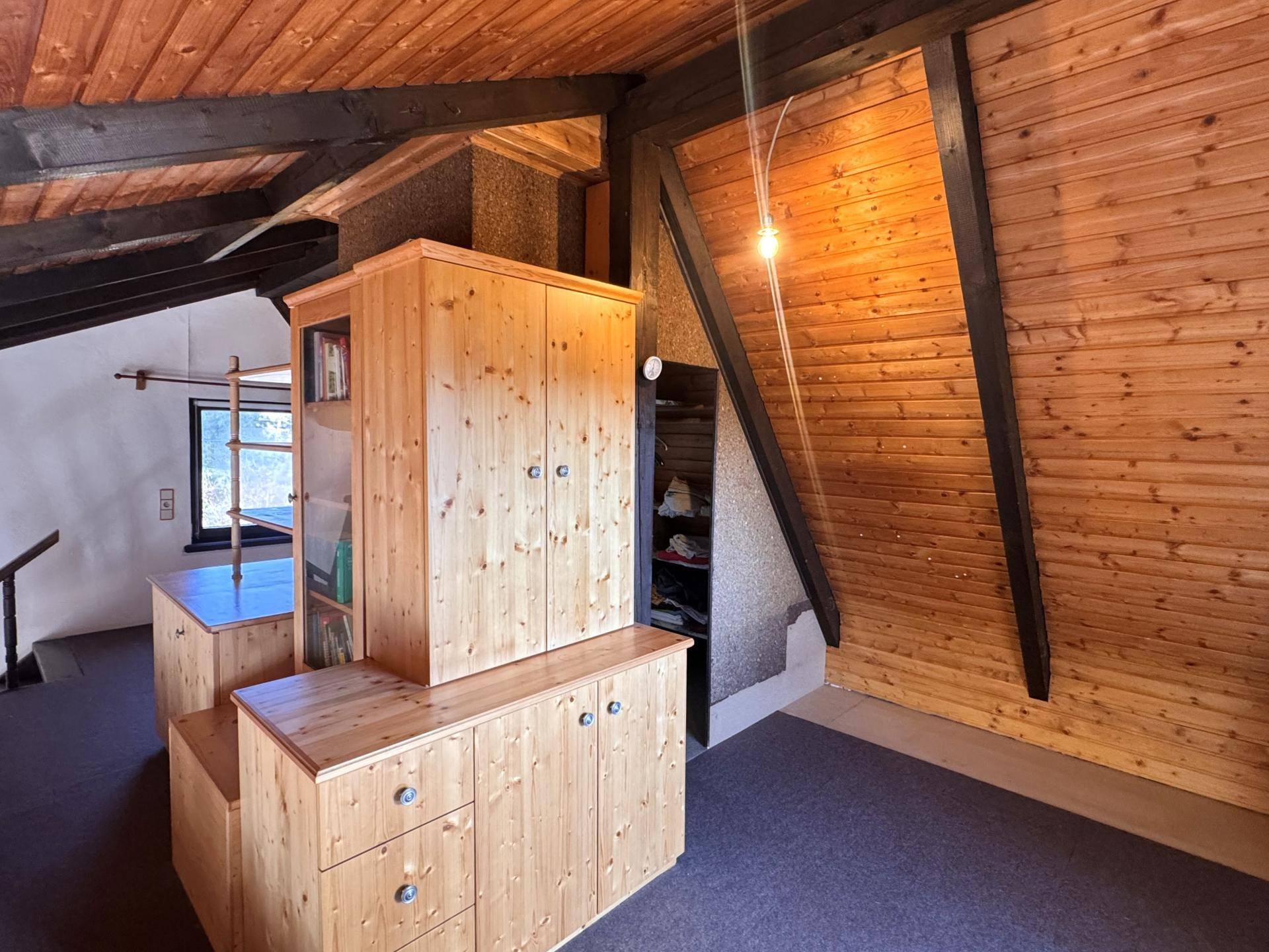Gemütlicher Dachbodenraum mit Holzverkleidung und Einbauschränken, bietet zusätzlichen Stauraum.