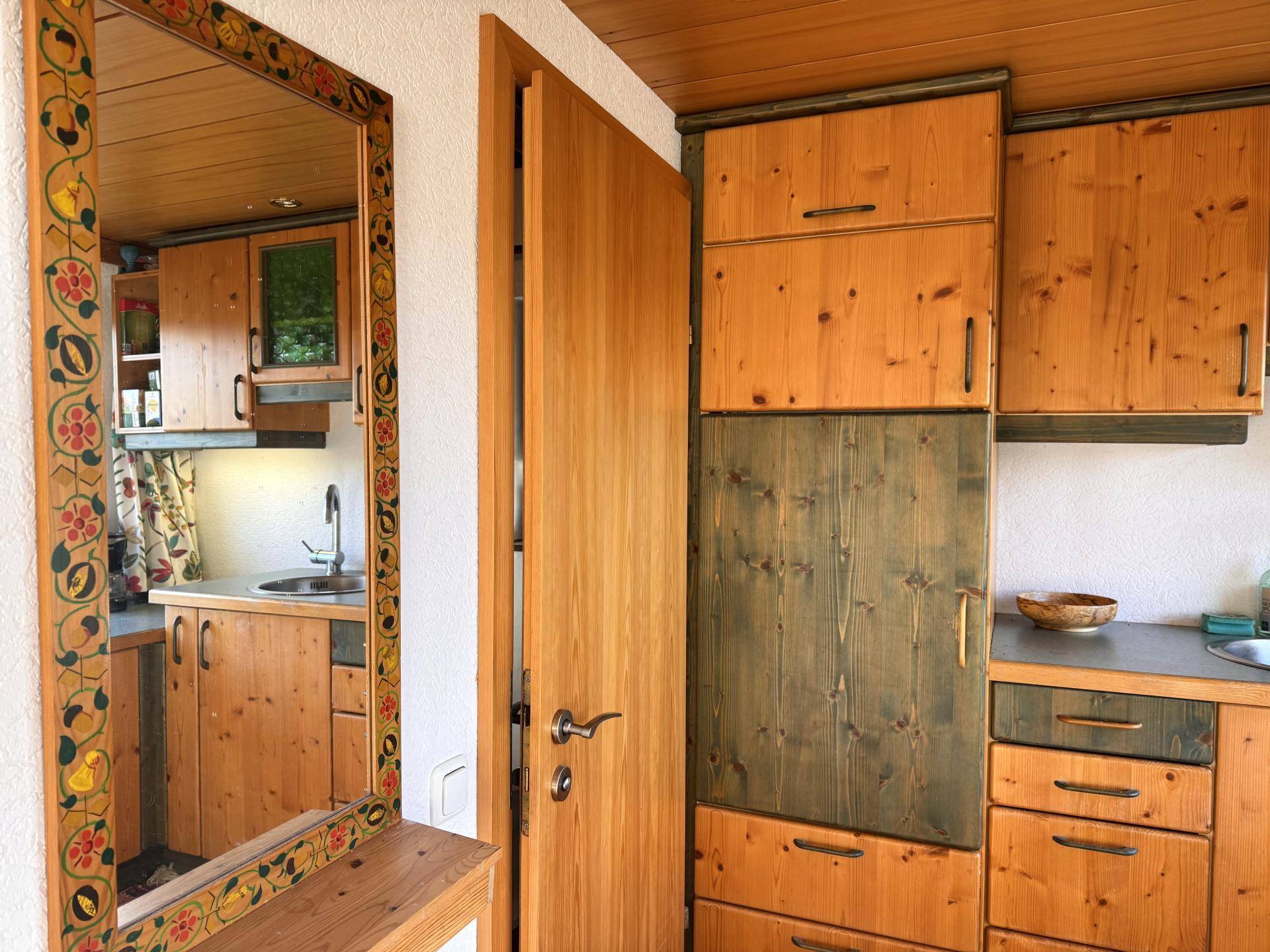 Traditionelle Holzküche mit Spüle und Schränken, gespiegelt in einem dekorativen Wandspiegel.