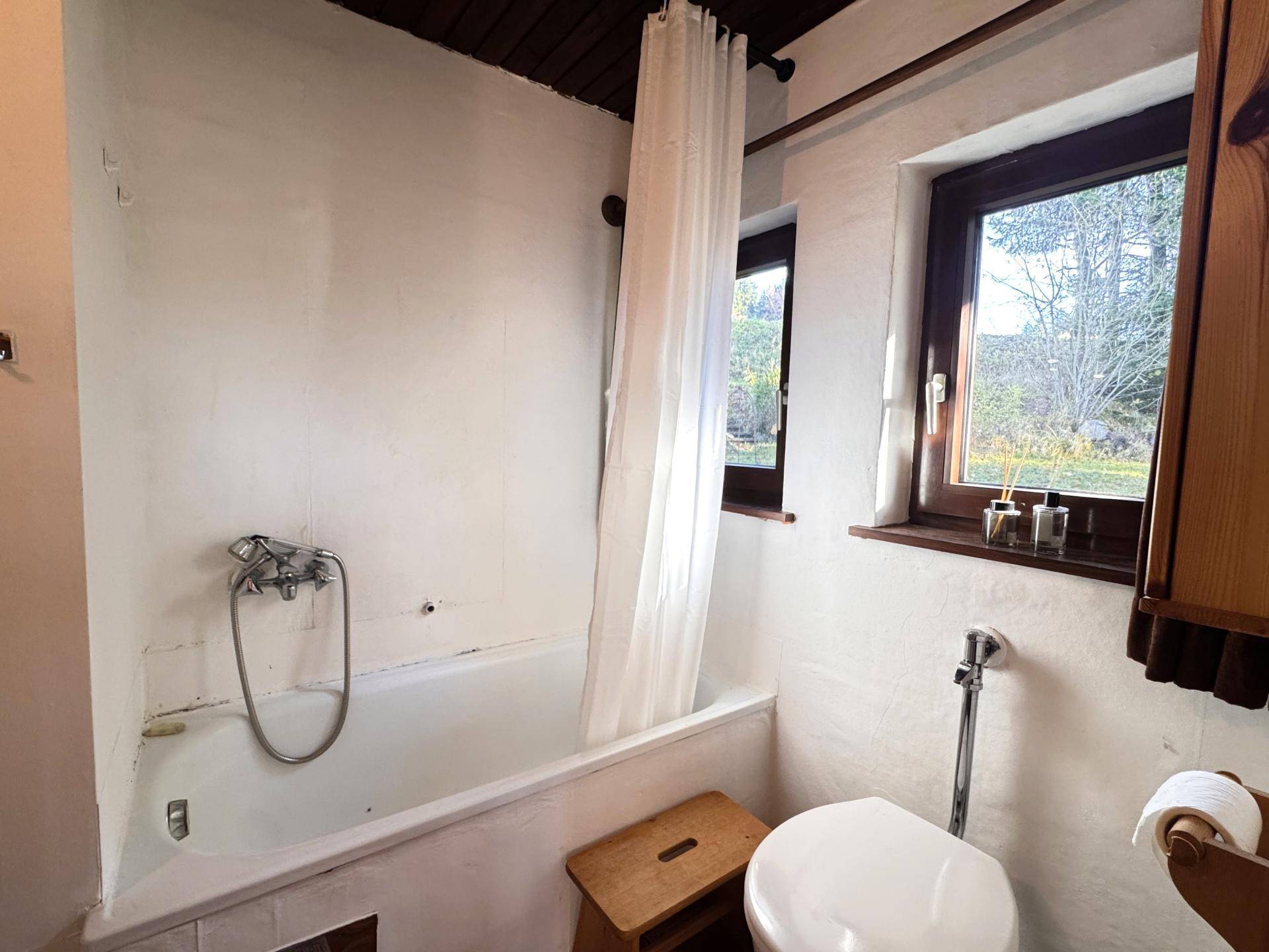 Helles Badezimmer mit Badewanne, Toilette und Fenster, bietet natürliche Belüftung.