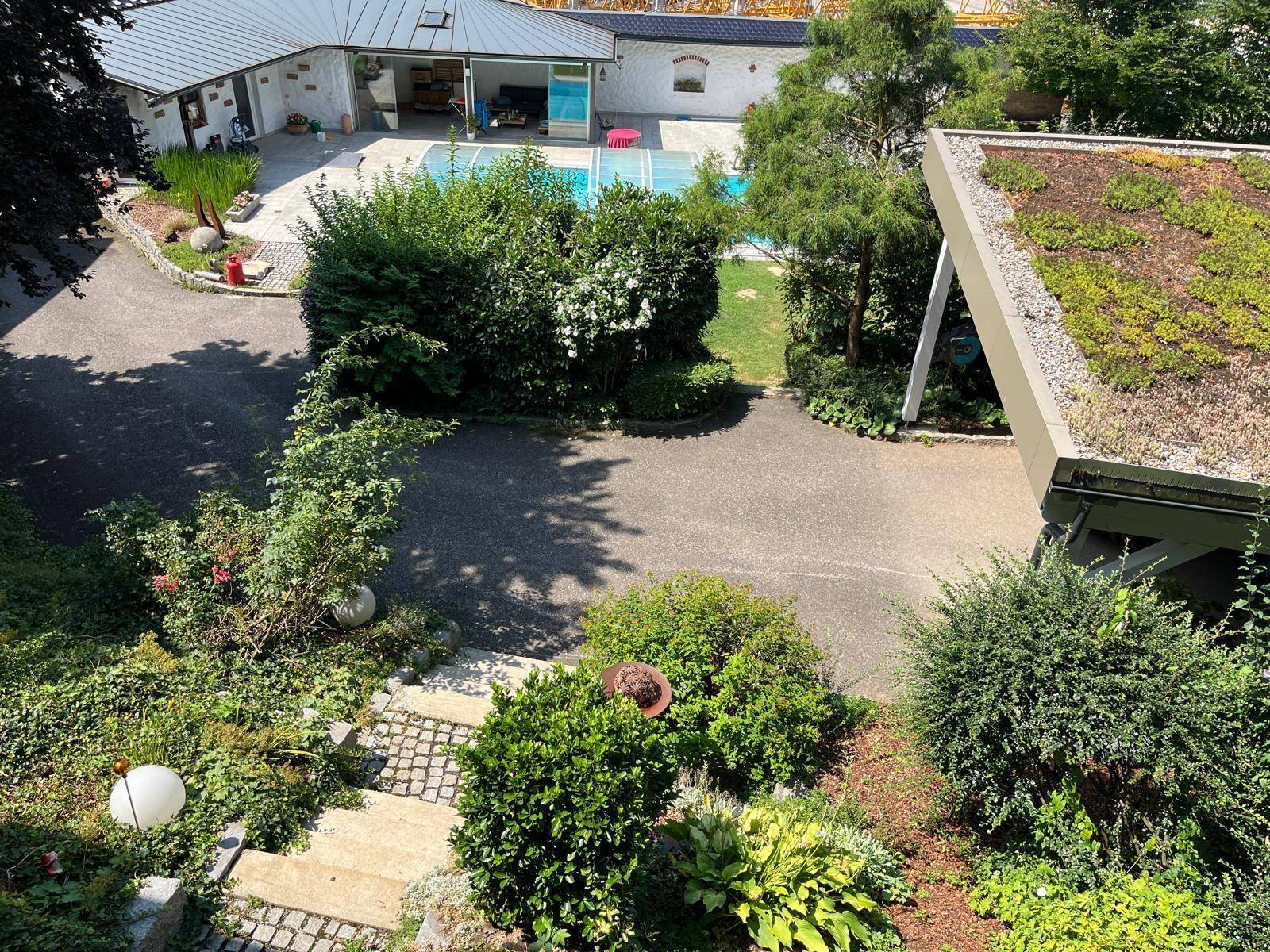 Vogelperspektive auf ein Anwesen mit gepflegtem Garten, Poolbereich und weiteren Gebäuden.