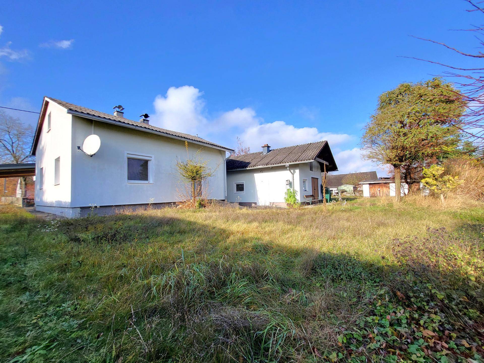 Weitläufiger Garten mit Rasenfläche und Blick auf das Wohnhaus und ein Nebengebäude.