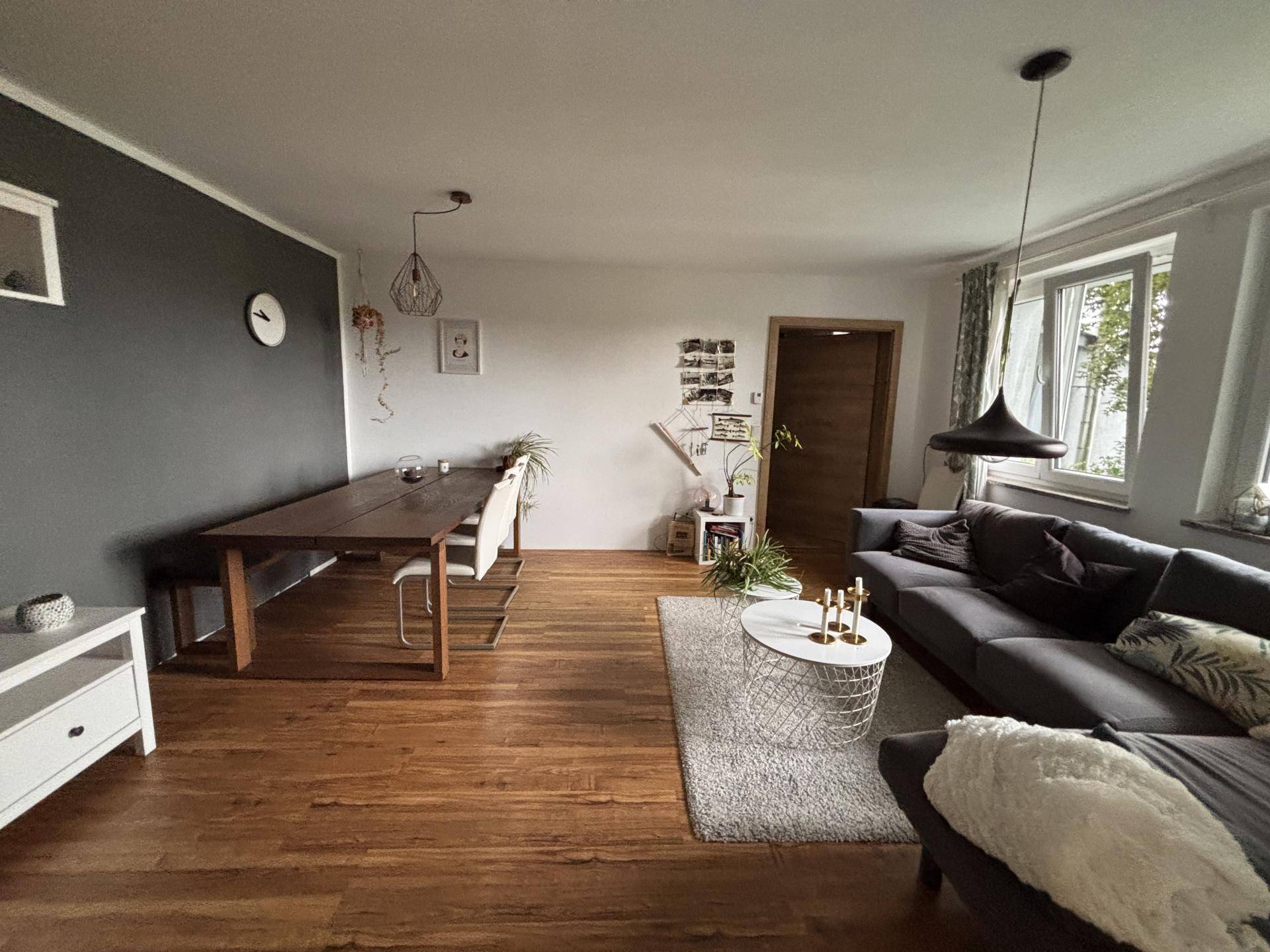 Offener Wohn-Essbereich mit Holzboden, großem Sofa und Esstisch in modernem Stil.