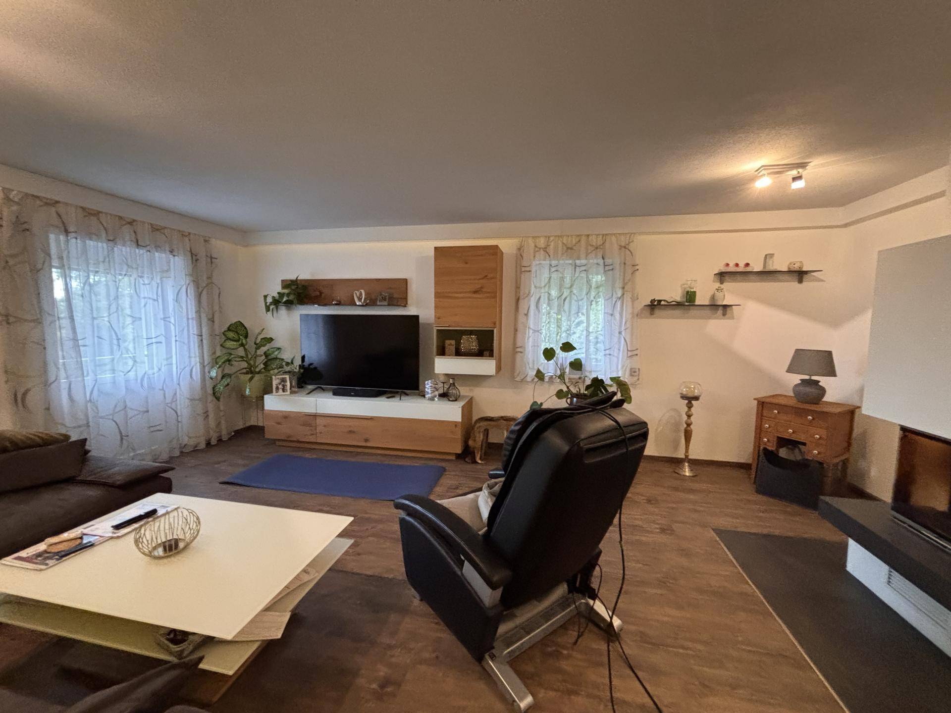 Gemütliches Wohnzimmer mit Holzboden, großem Sofa und einem modernen Kamin.