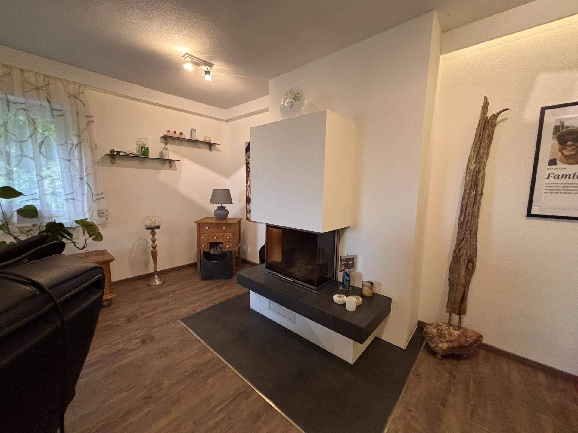 Wohnzimmer mit modernem Kamin, Holzboden und dekorativen Elementen.