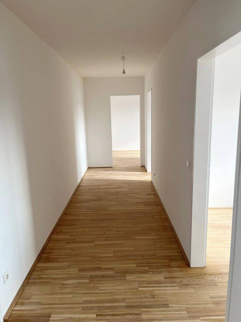 Langer, heller Flur mit Holzboden, der zu weiteren Zimmern führt.