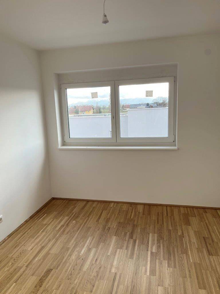 Helles Schlafzimmer mit Holzboden und großem Fenster, bietet viel Tageslicht.