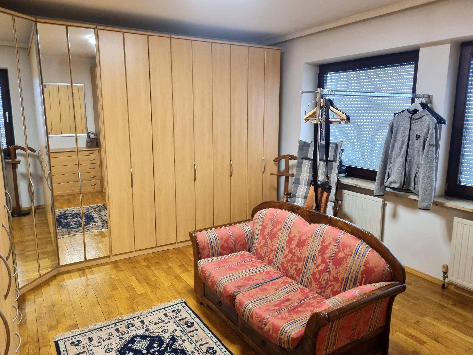 Geräumiges Zimmer mit großen Einbauschränken, Sofa und Holzfußboden, vielseitig nutzbar.