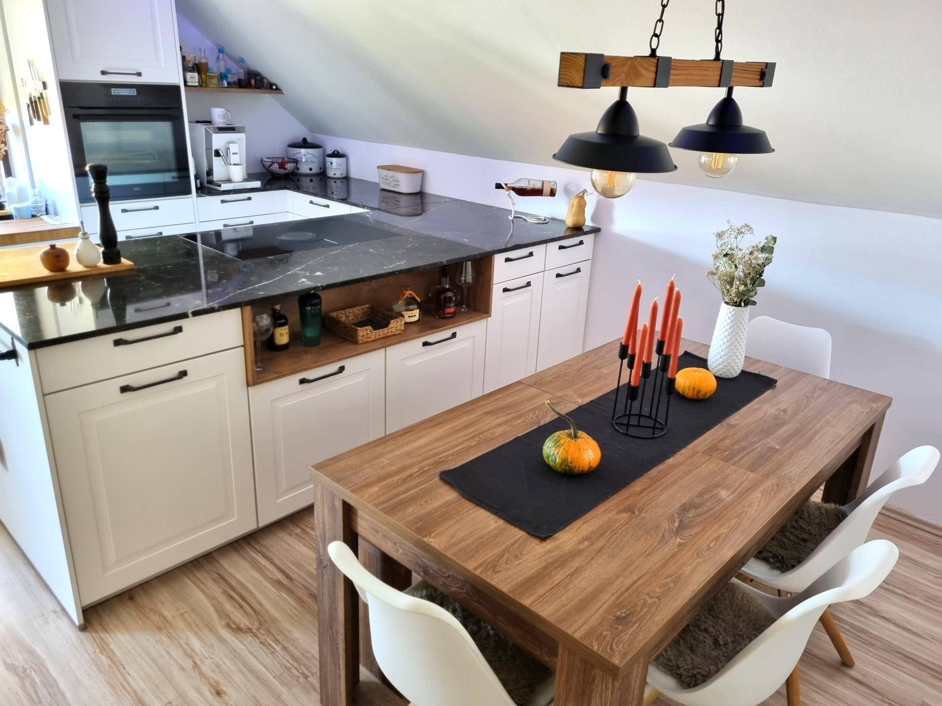 Moderne Küche mit Kochinsel, Essbereich und Dachschrägen, ideal für offenes Wohnen im Dachgeschoss.