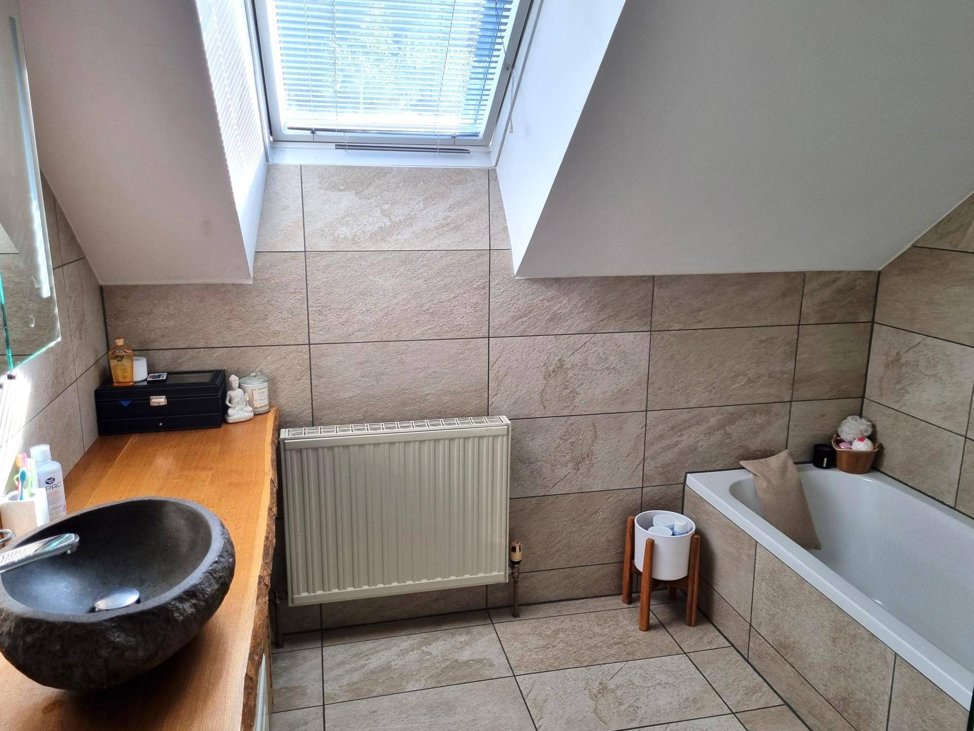 Helles Badezimmer im Dachgeschoss mit Dachfenster, Waschtisch und Badewanne für entspannende Momente.