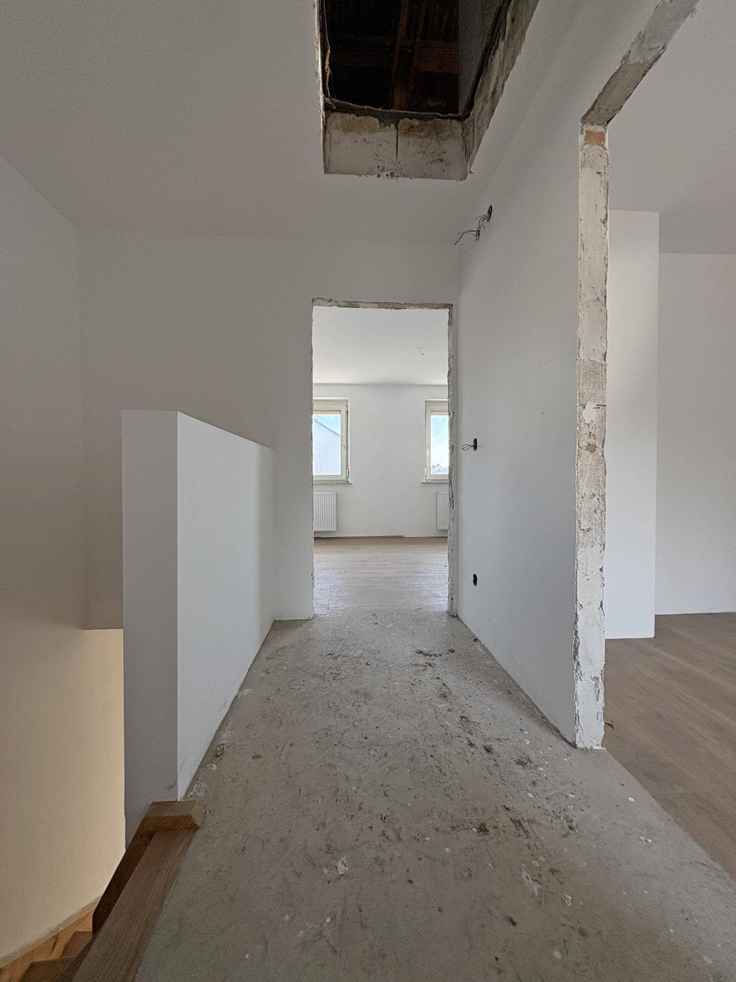 Flur im Rohbauzustand mit Blick in weitere Räume, die ebenfalls renoviert werden.