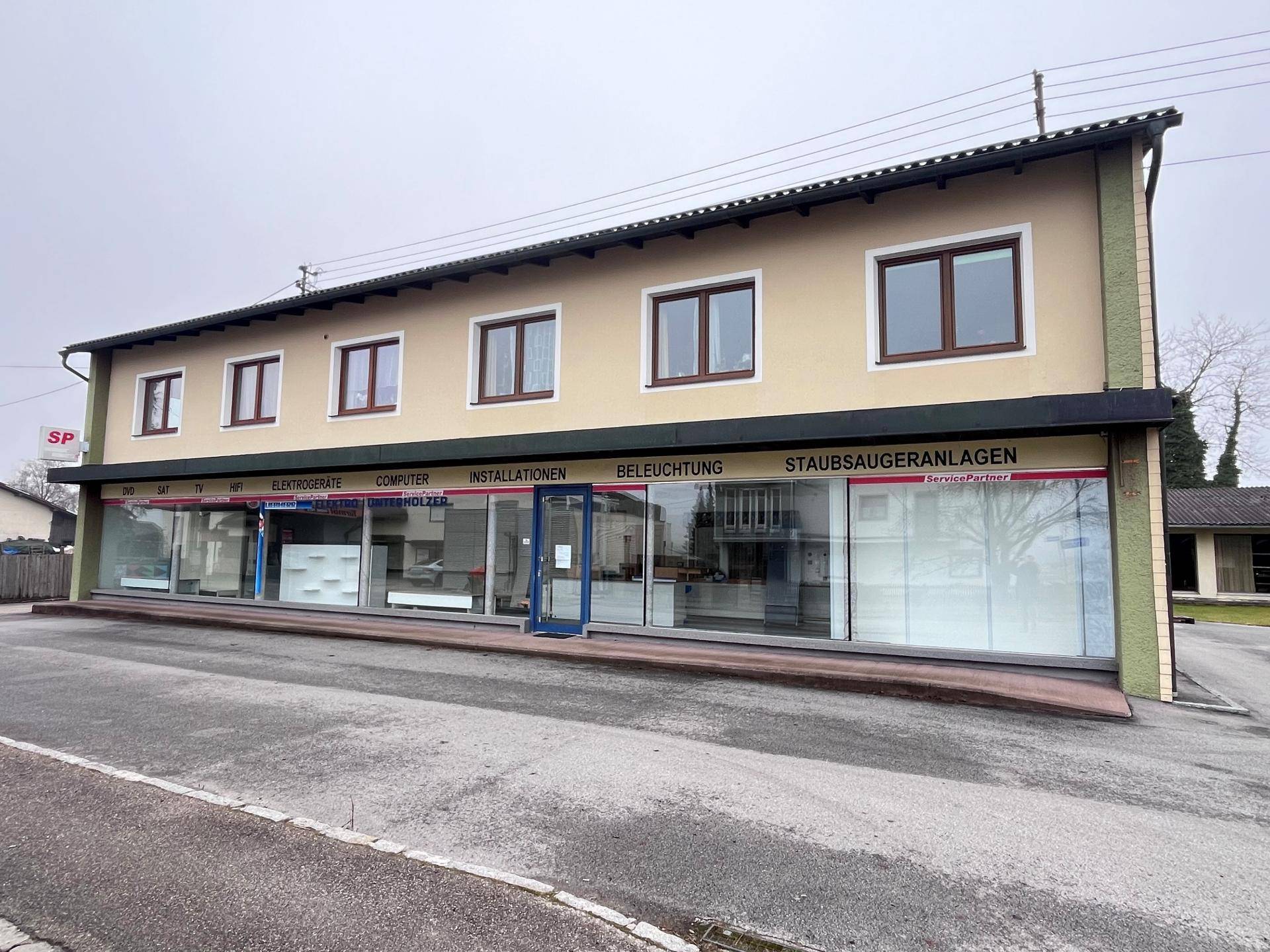 Seitenansicht des Gewerbegebäudes mit Schaufenstern und angrenzender Straße.