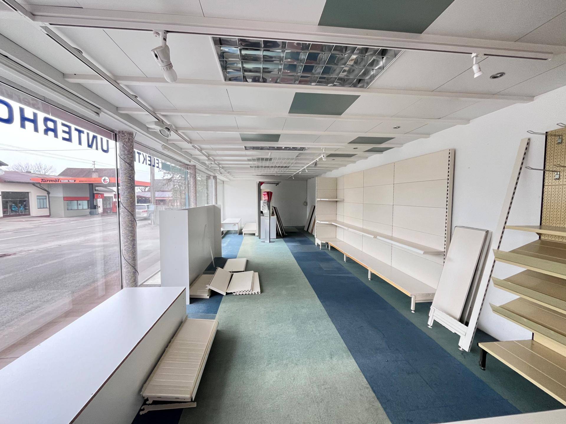 Gewerbefläche mit Teppichboden, Regalsystemen und Blick auf die Straße.