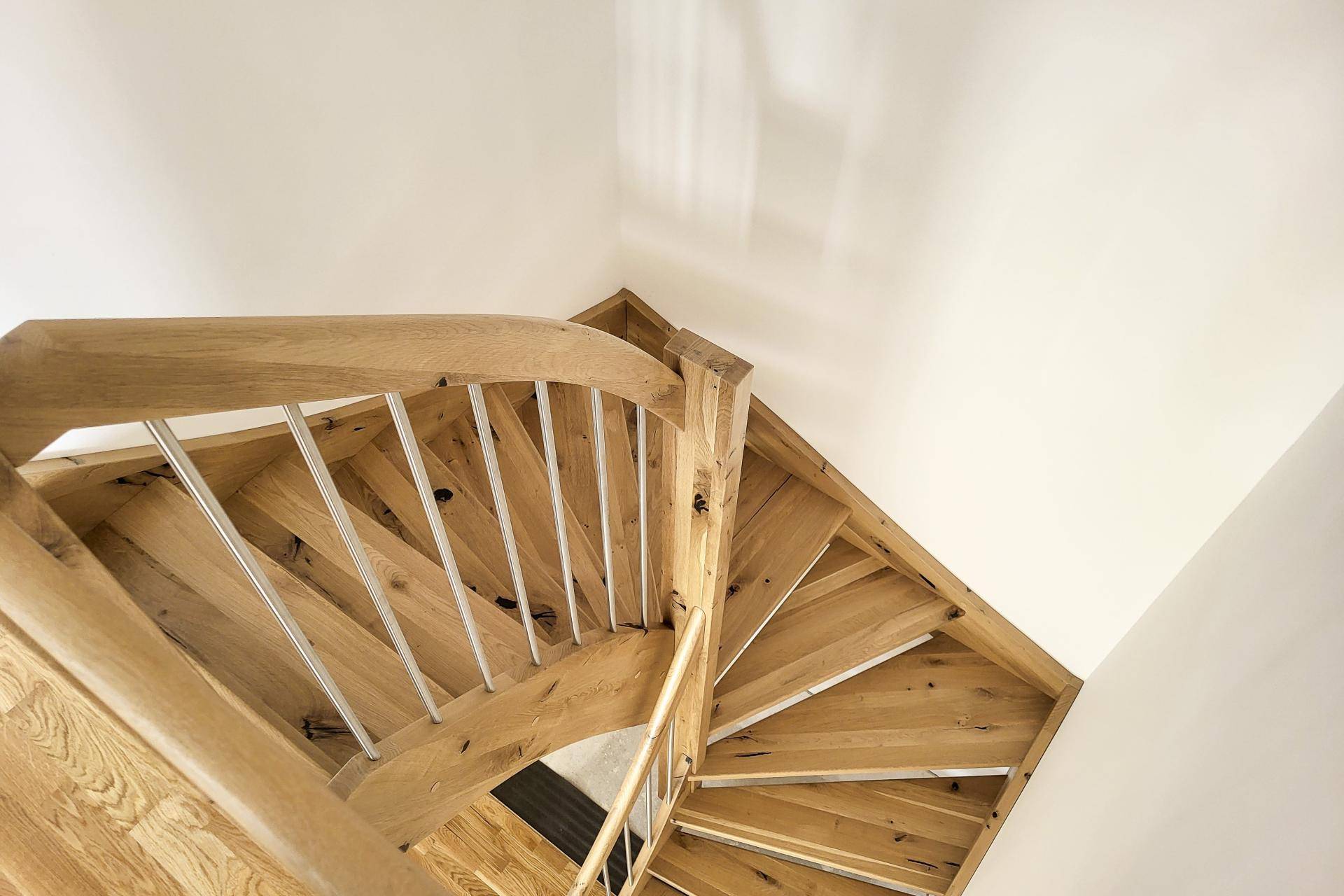 Elegante Holztreppe mit modernen Metallgeländern, die verschiedene Etagen des Hauses verbindet.