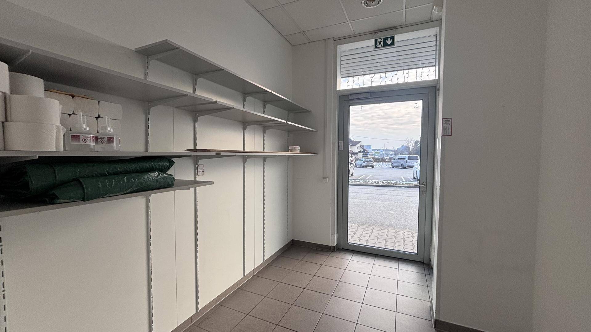 Praktischer Lagerraum mit Regalsystemen und einer Ausgangstür, die zu einem Parkplatz führt.