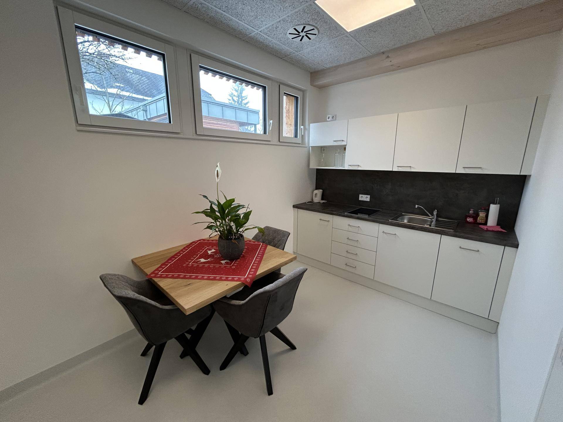 Kleine, moderne Küchenzeile mit Esstisch und Stühlen, ausgestattet mit Spüle und Kochfeld.