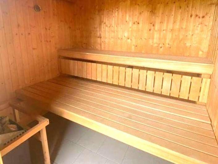 Gemütliche Holzsauna mit mehreren Bänken und traditionellem Saunaofen für Entspannung.