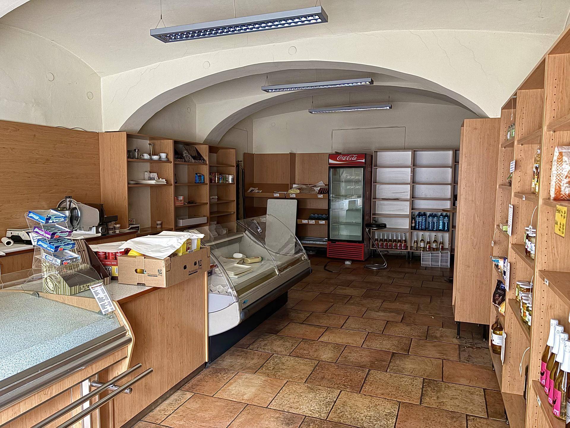 Innenansicht eines Ladengeschäfts mit gewölbter Decke, Fliesenboden und leeren Regalen.