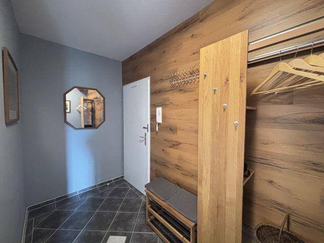 Heller Eingangsbereich mit dunklen Fliesen, Holzvertäfelung und praktischer Garderobe.