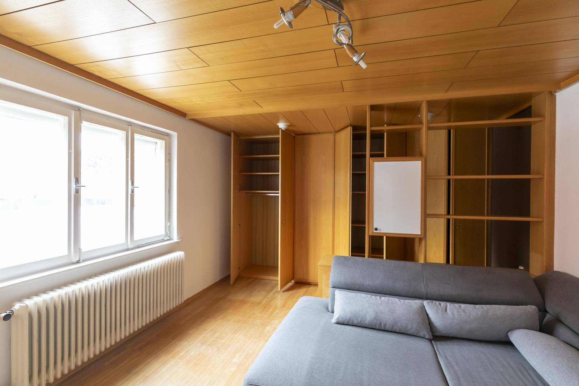 Wohnzimmer mit Holzdecke, Einbauschränken und großem Fenster für viel Tageslicht.