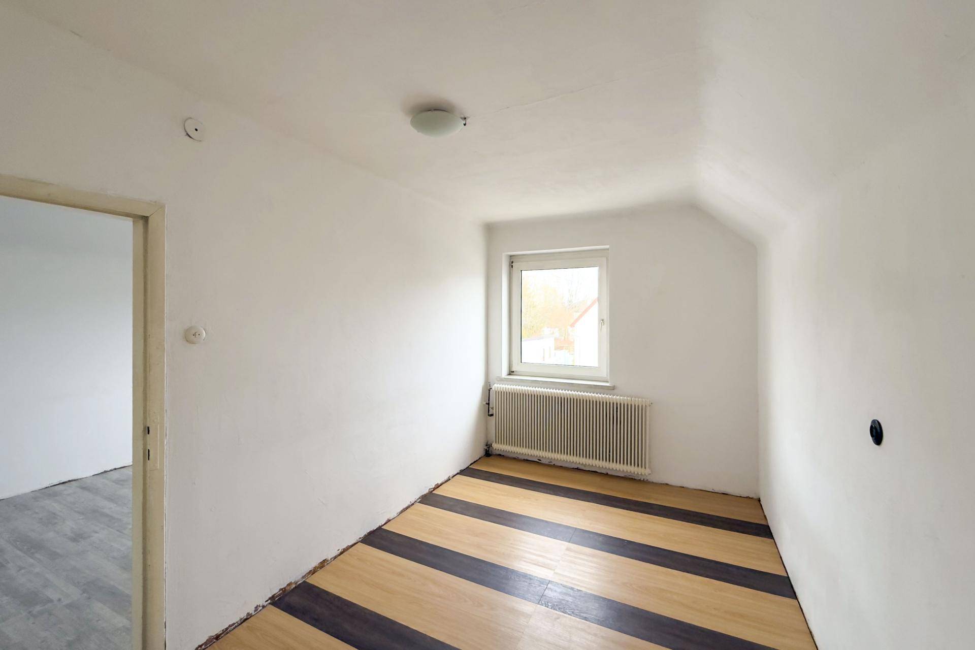 Weiterer Raum im Dachgeschoss mit Laminatboden und einem Fenster für natürliche Belichtung.