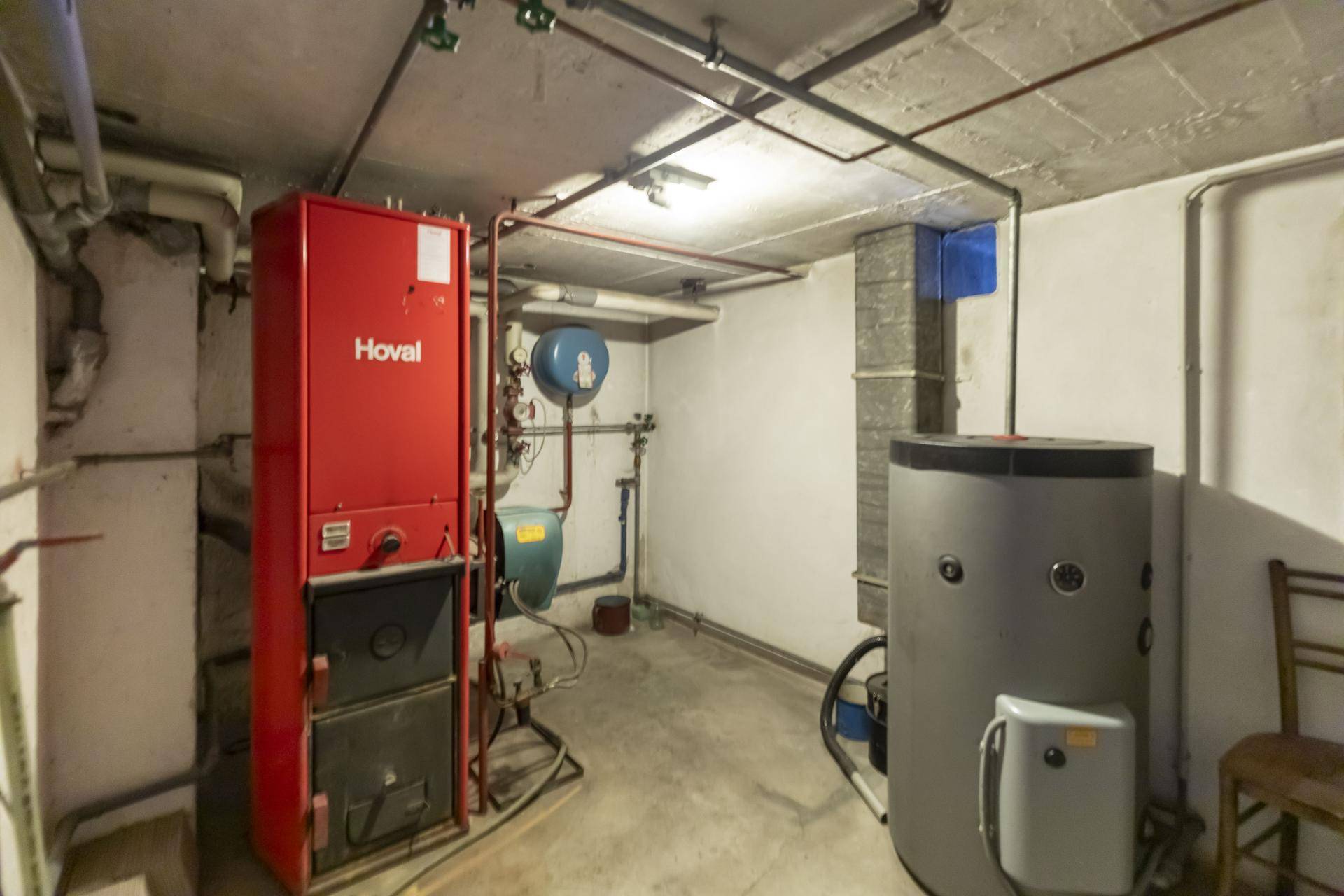 Heizungsraum im Keller mit großem Heizkessel und Warmwasserspeicher.